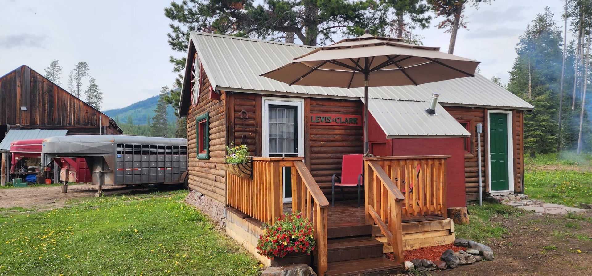 A small log cabin with a porch and an umbrella in front of it.