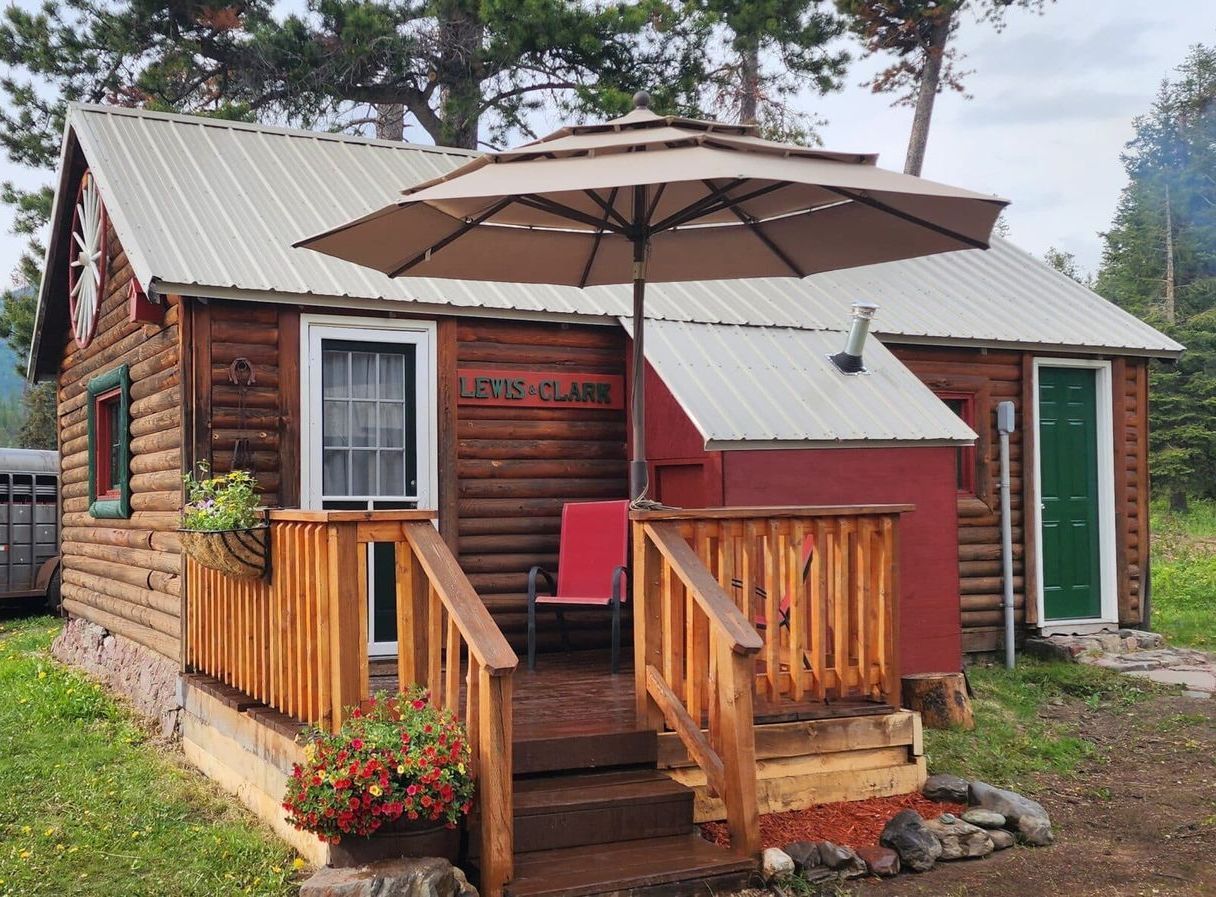 A small log cabin with an umbrella on the porch.