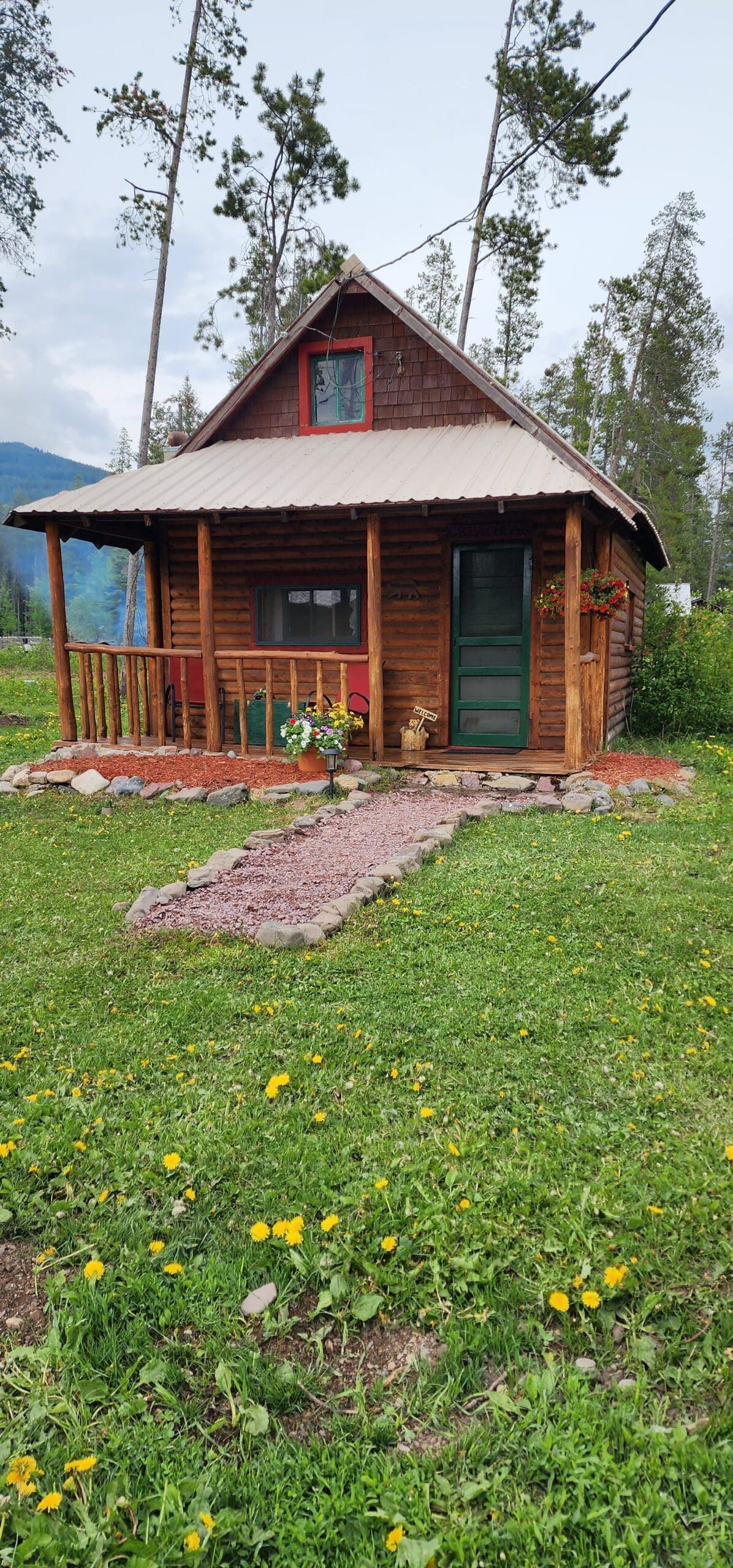 A small log cabin is sitting in the middle of a grassy field.