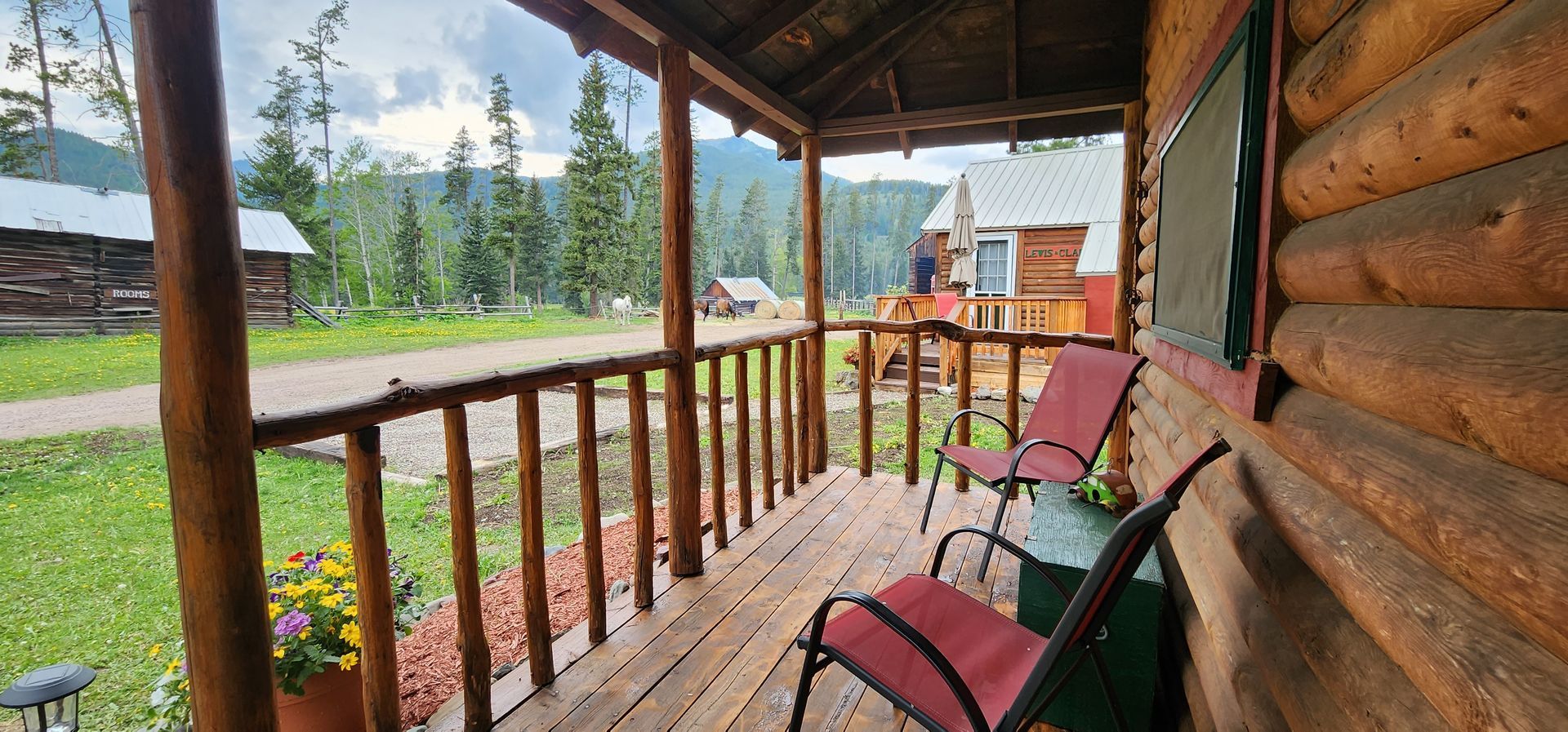 There are two chairs on the porch of a log cabin.