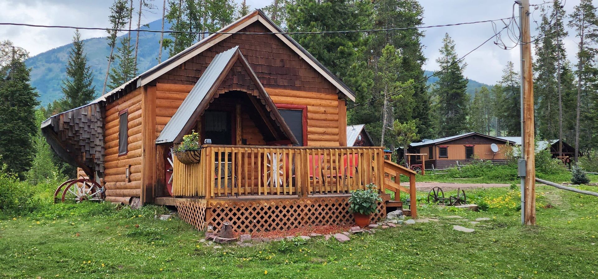 A small log cabin with a porch in the middle of a grassy field.