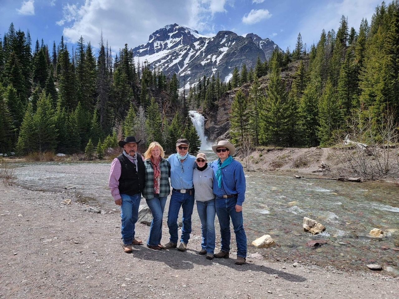 A group of people are posing for a picture in front of a waterfall.