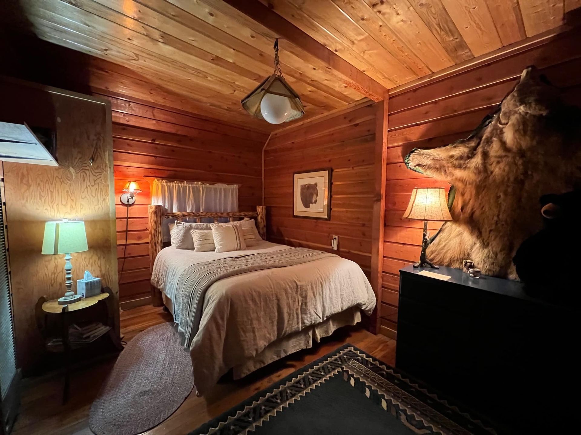 A bedroom with a bed , lamps , and a stuffed animal on the wall.