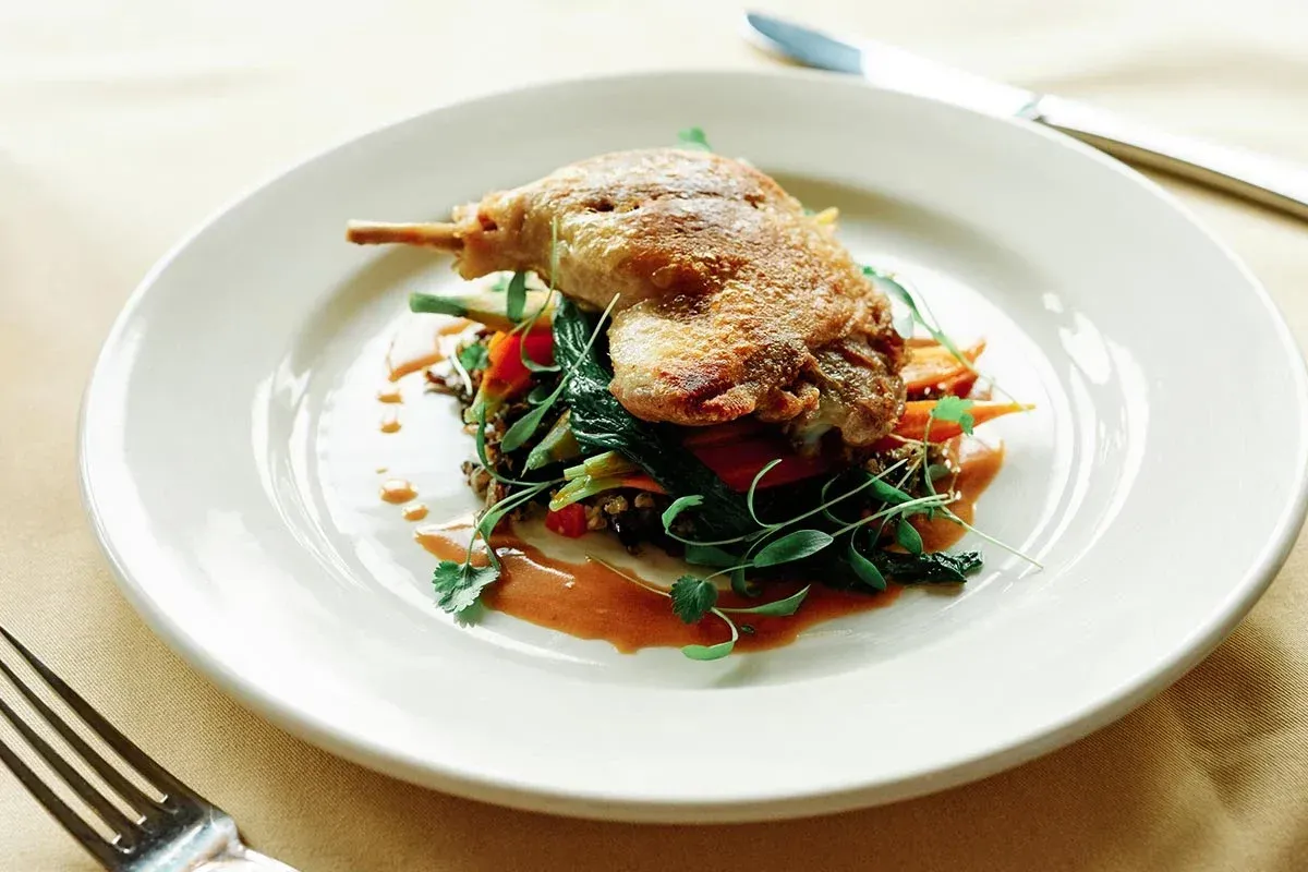 A plate of food with a fork on a wooden table.