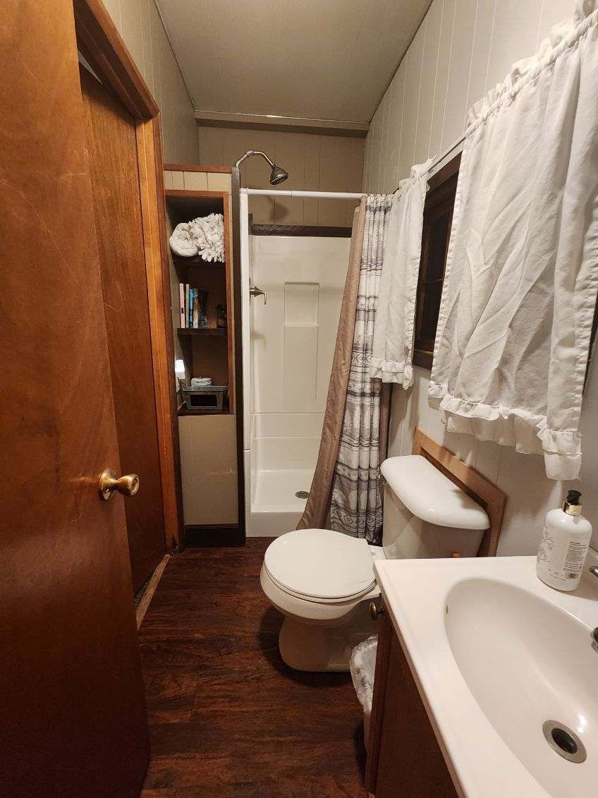 A bathroom with a toilet , sink and shower.