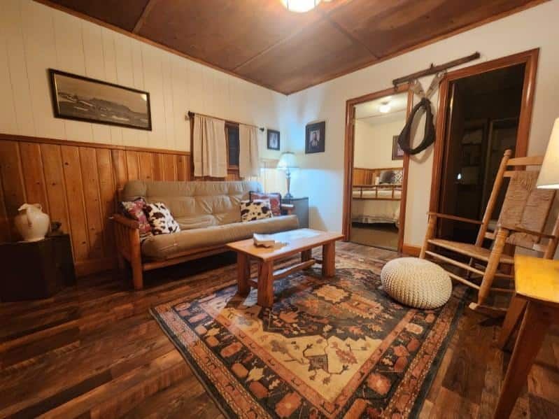 A living room with a couch , rocking chair , coffee table and rug.