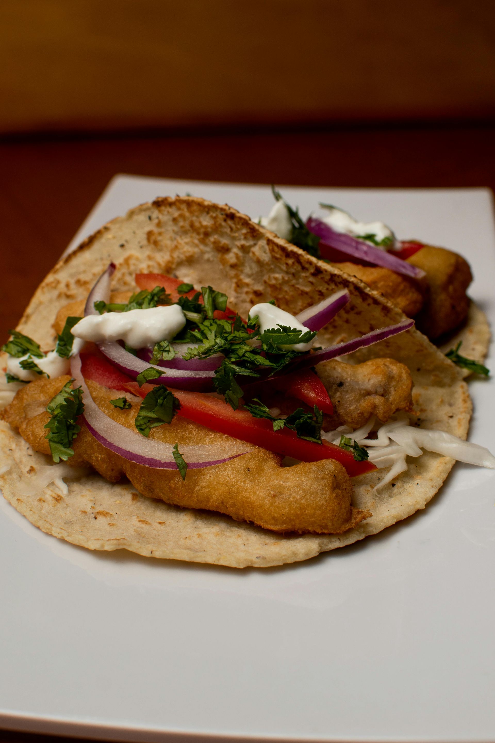A close up of a fish taco on a white plate.