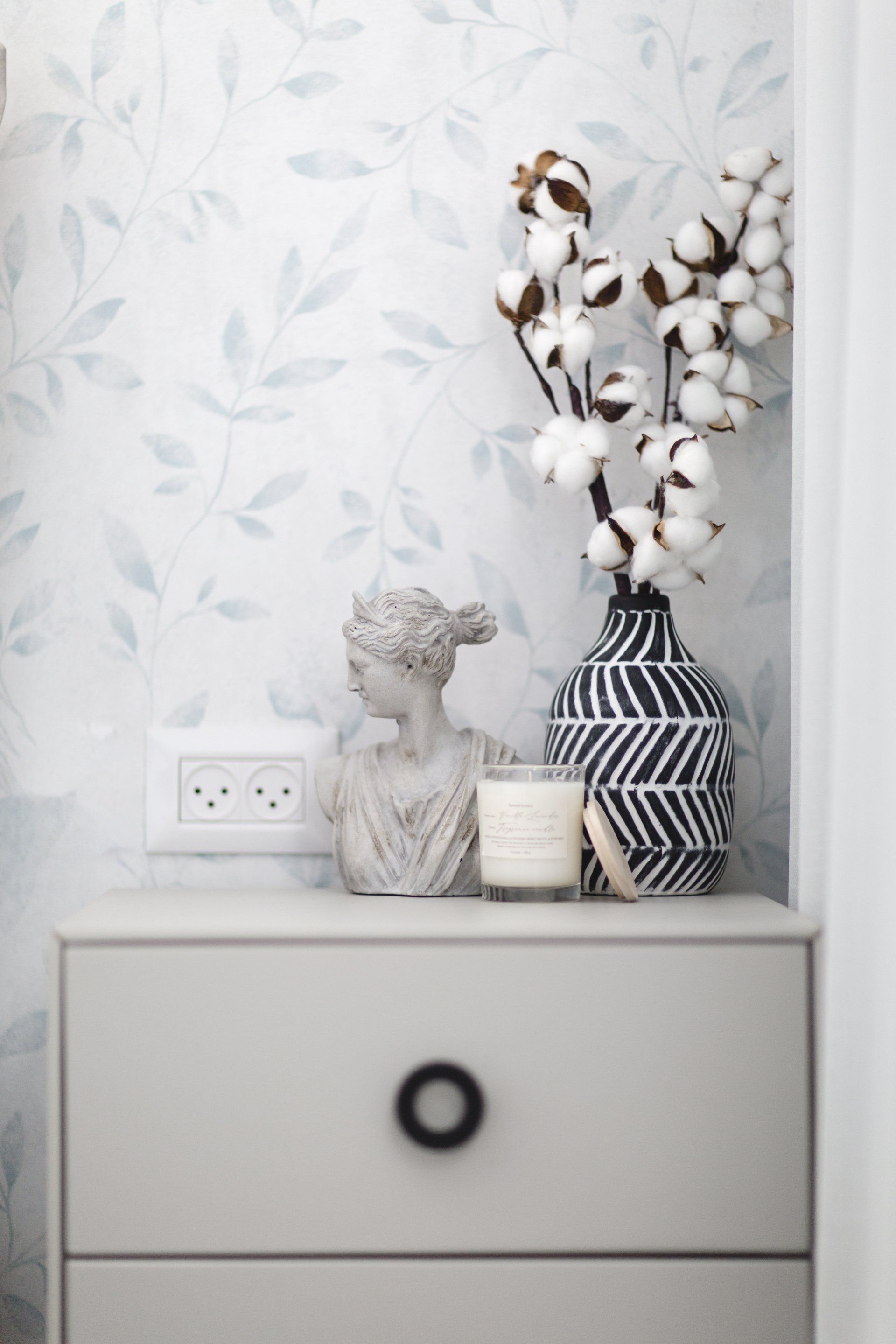 ענפי כותנה, נר ריחני ופסל קטן  לישון בסוויטה פסטלית בעיצוב של מעצבת פנים ומלבישה בתים ג׳ני ויאליך jenyvstudio