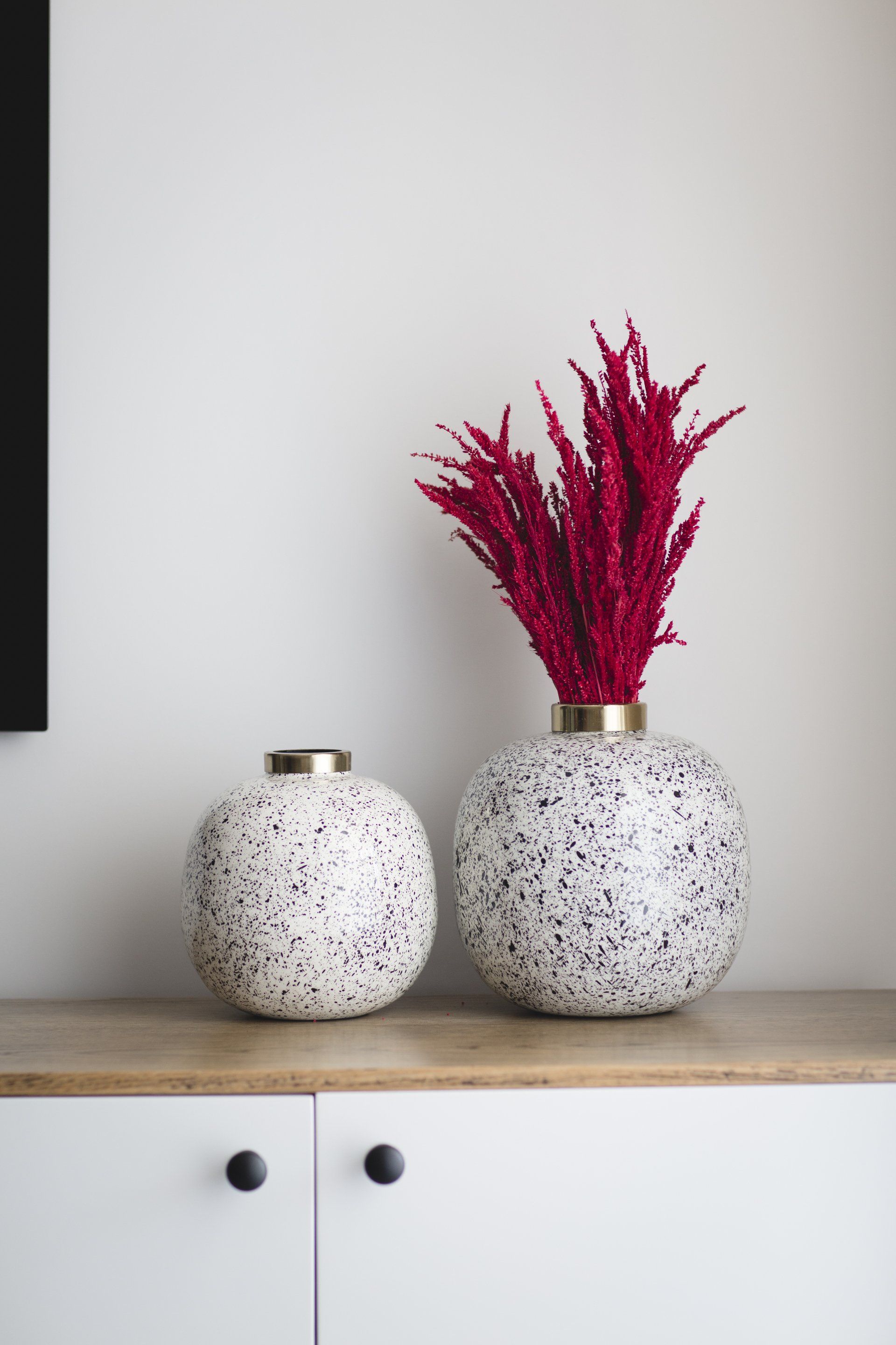 אגרטלים עם צמחים יבשים בצבע אדום בולט סוויטת הורים מרווחת ואלגנטית בגוונים מרגיעים עם אלמנטים של עיצוב  מיוחדים חלל ציבורי אלגנטי בעיצוב של מעצבת פנים ומלבישה בתים ג׳ני ויאליך jenyvstudio