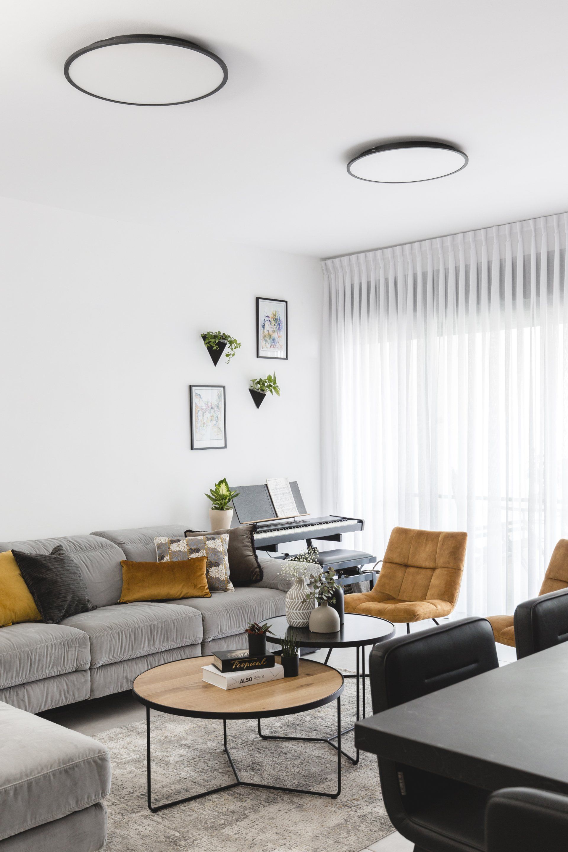 הלבשת חלל סלון ומטבח בגווני אפור שחור וחרדל. שפע של צמחים.  שחור-אפור וכל מה שבניהם בעיצוב של מעצבת פנים ומלבישה בתים ג׳ני ויאליך jenyvstudio