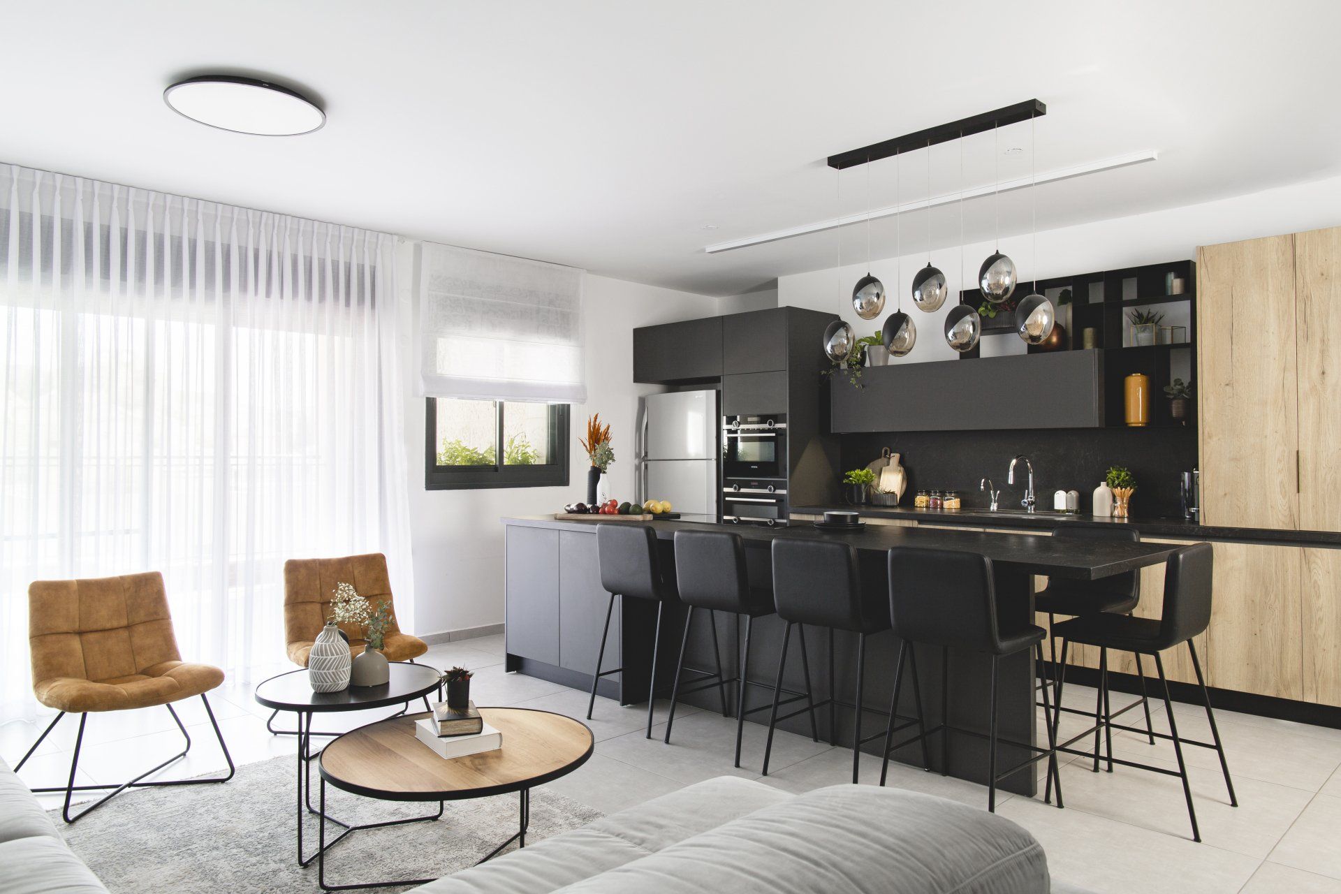 הלבשת חלל סלון ומטבח בגווני אפור שחור וחרדל. שפע של צמחים.  שחור-אפור וכל מה שבניהם בעיצוב של מעצבת פנים ומלבישה בתים ג׳ני ויאליך jenyvstudio