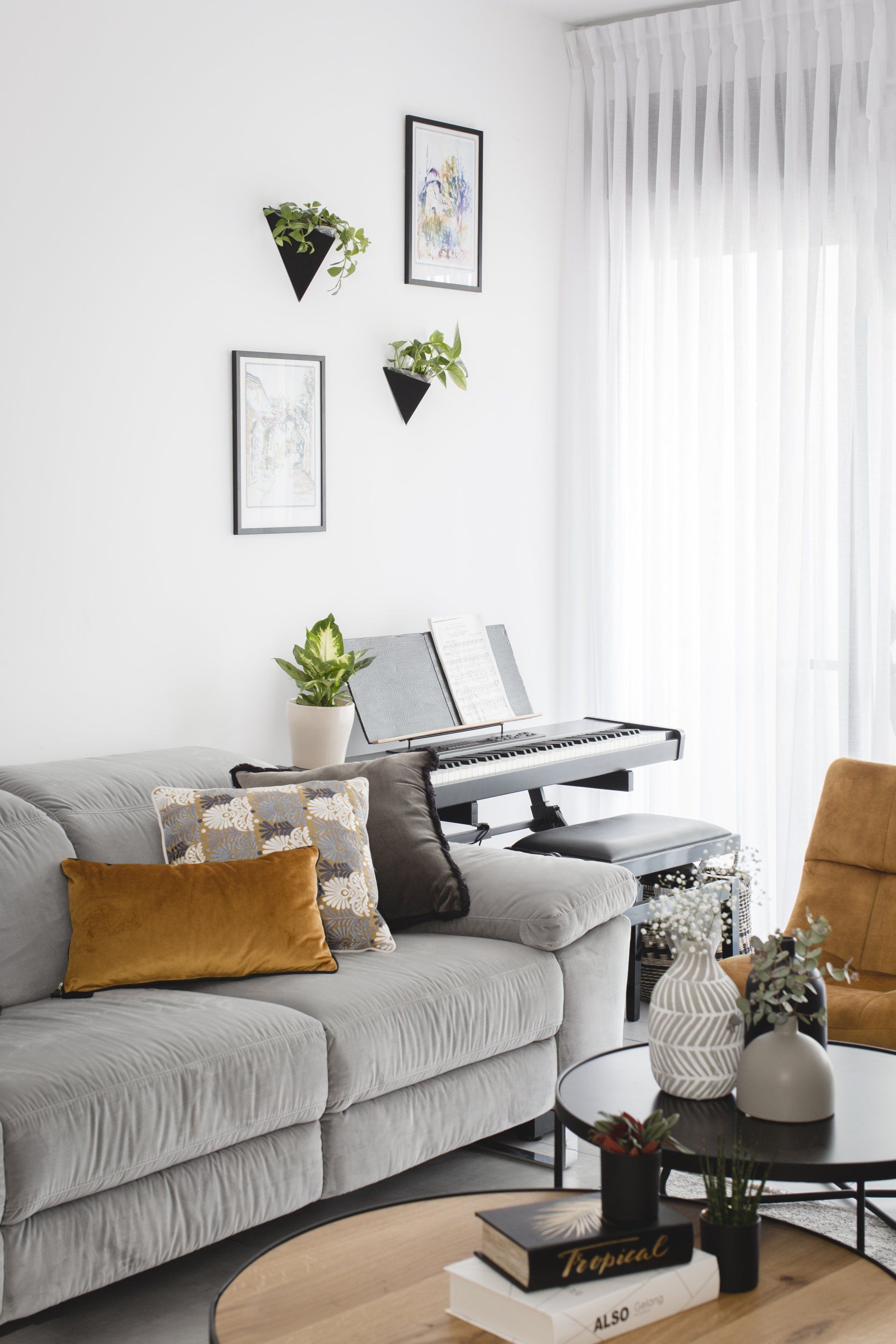 הלבשת חלל סלון ומטבח בגווני אפור שחור וחרדל. שפע של צמחים.  שחור-אפור וכל מה שבניהם בעיצוב של מעצבת פנים ומלבישה בתים ג׳ני ויאליך jenyvstudio