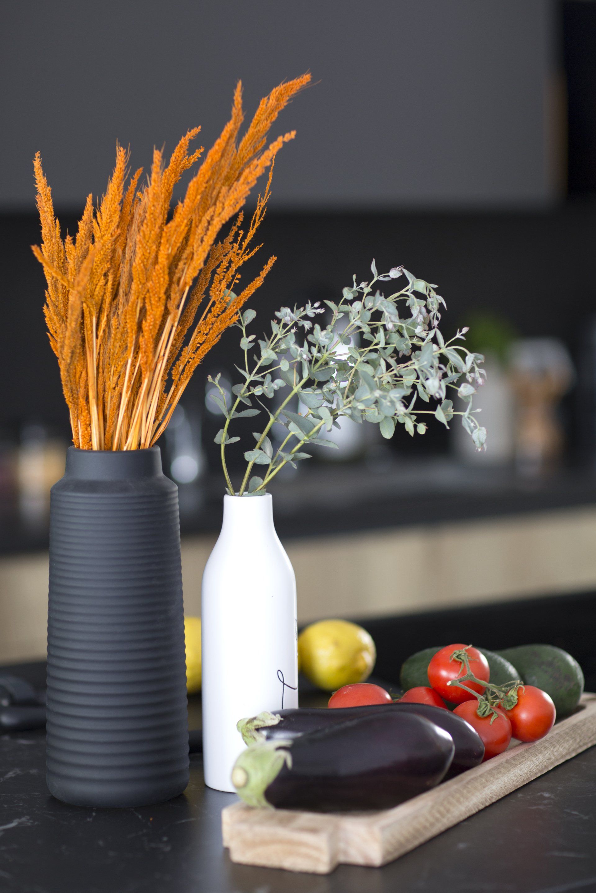 הלבשת חלל סלון ומטבח בגווני אפור שחור וחרדל. שפע של צמחים.  שחור-אפור וכל מה שבניהם בעיצוב של מעצבת פנים ומלבישה בתים ג׳ני ויאליך jenyvstudio