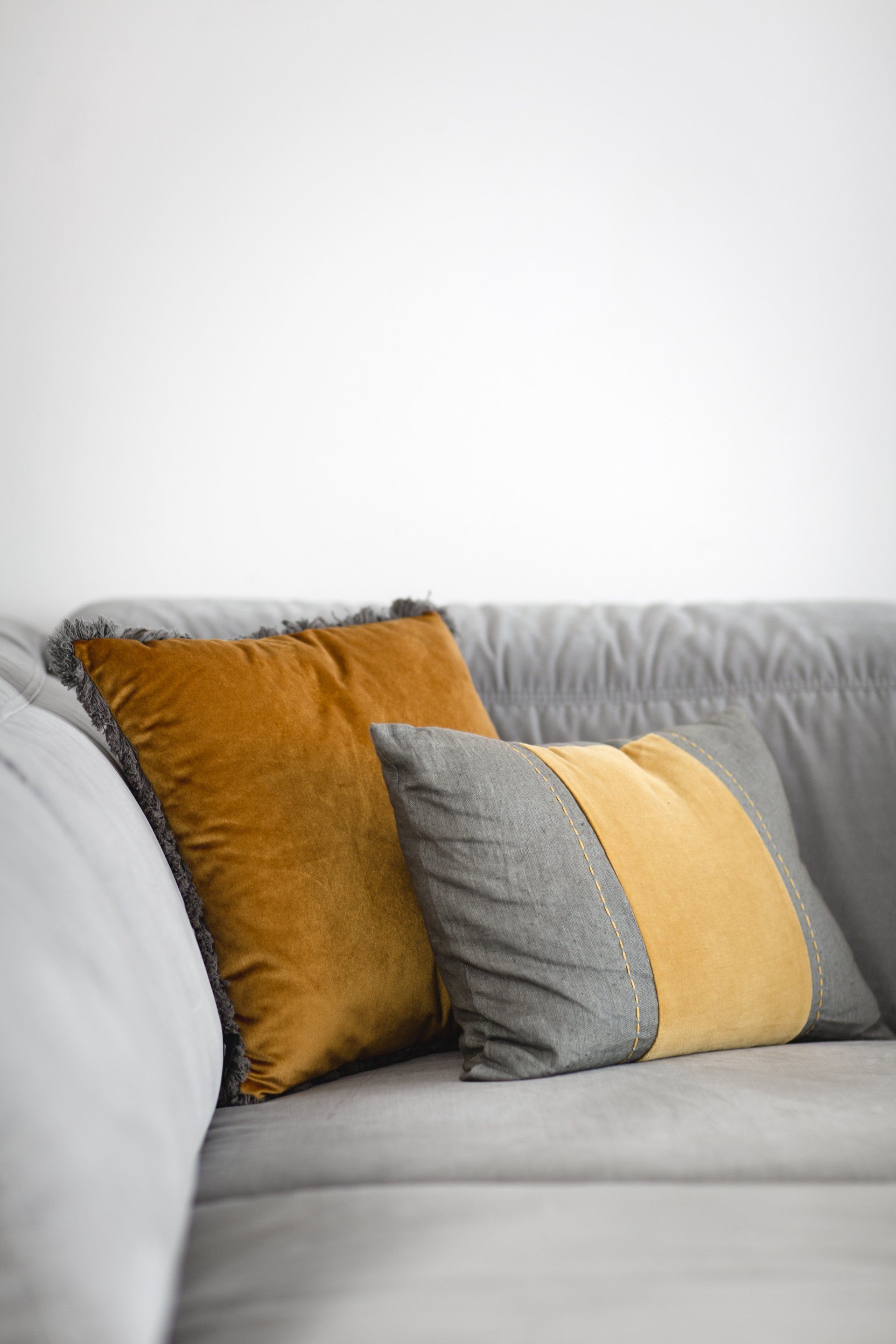 כריות נוי בצבע חרדל הלבשת חלל סלון ומטבח בגווני אפור שחור וחרדל. שפע של צמחים.  שחור-אפור וכל מה שבניהם בעיצוב של מעצבת פנים ומלבישה בתים ג׳ני ויאליך jenyvstudio