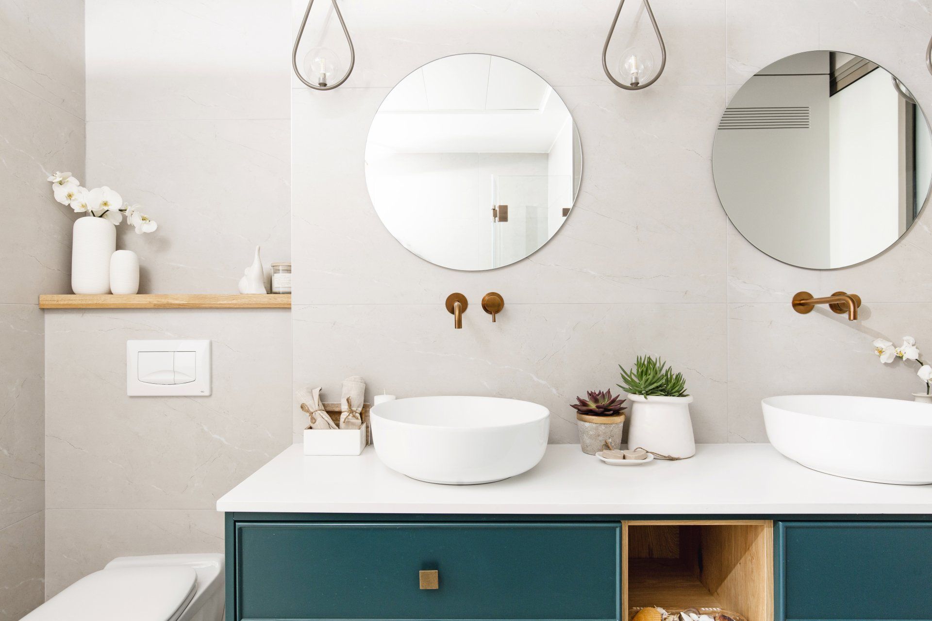 מדפי עץ, נרות ריחניים ופרחים לאוירה מושלמת וחמימה. שיפוץ מקלחת ילדים שבירת קיר והרחבת החלל. חדר אמבטיה לילדים עם שני כיורים ואלמנטים של זהב וצבע כחול. אריכים מיוחדים מקלחת ילדים חלומית בעיצוב של מעצבת פנים ומלבישה בתים ג׳ני ויאליך jenyvstudio