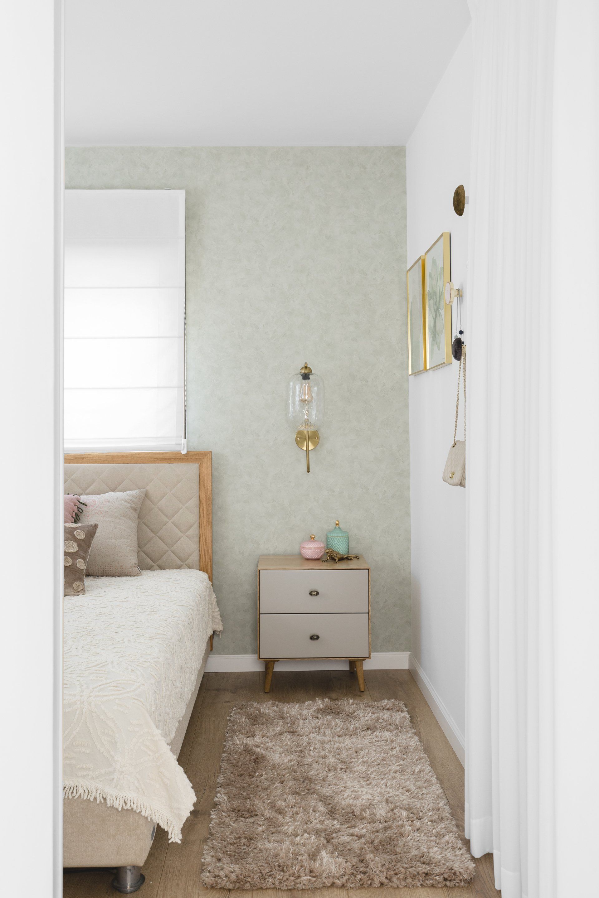 קיר ירוק בהיר בחדר שינה רומנטי מיטת עץ מצעים לבנים ושטיח חום