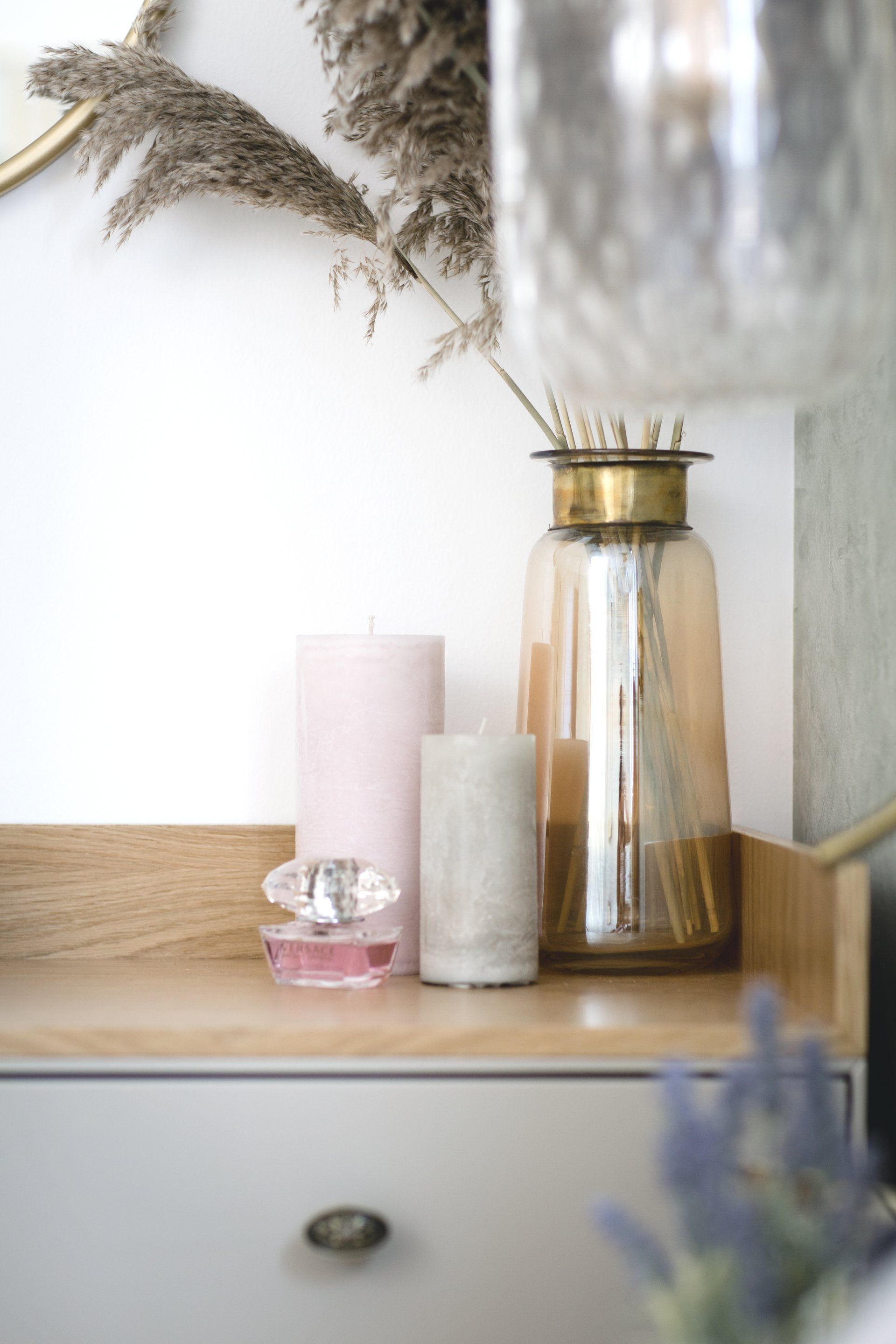 אגרטל מוזהב ונרות דקורטיבים מעל שידה