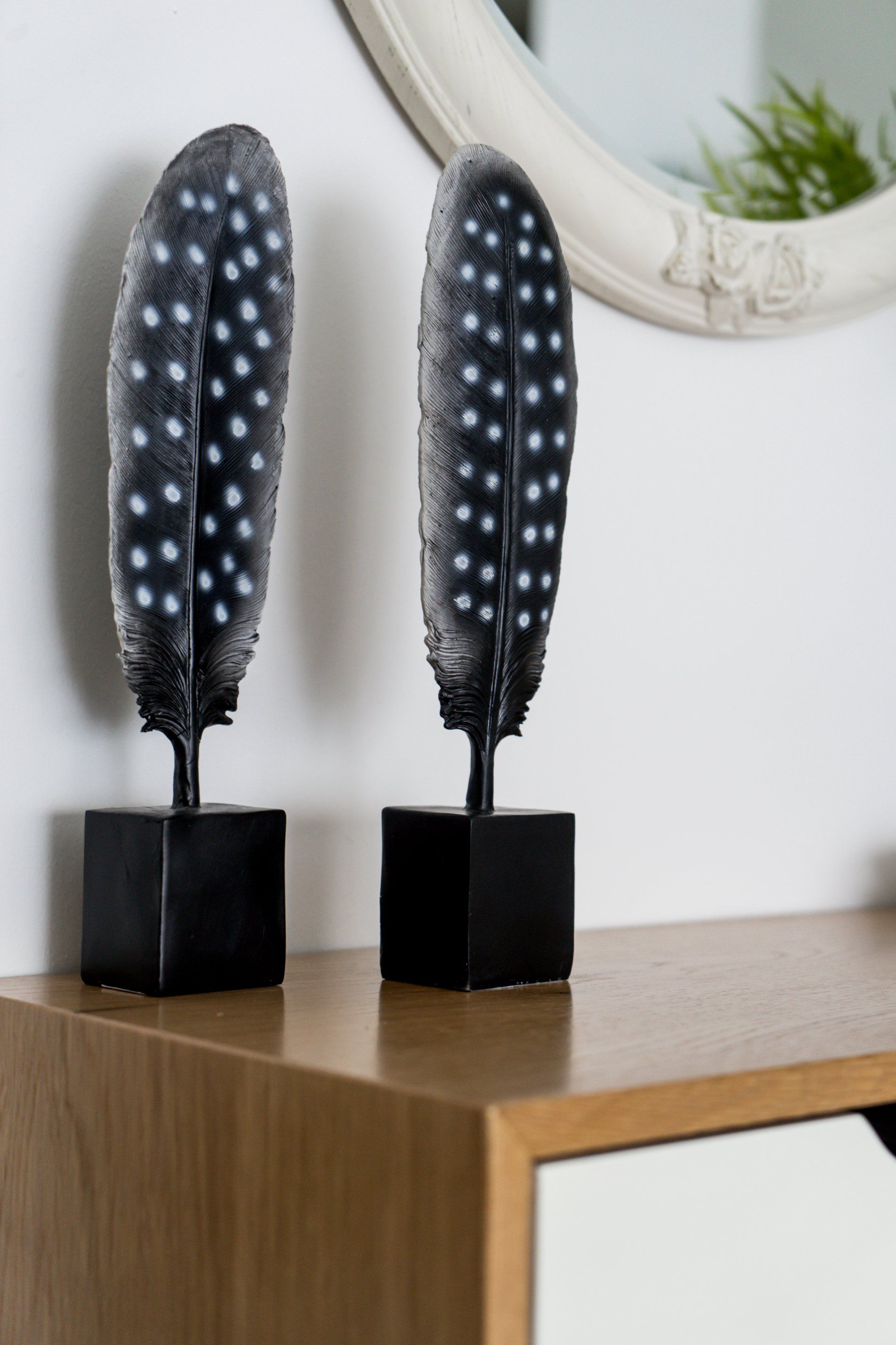 זוג פסלים דקורטיבים מעל שידת כניסה