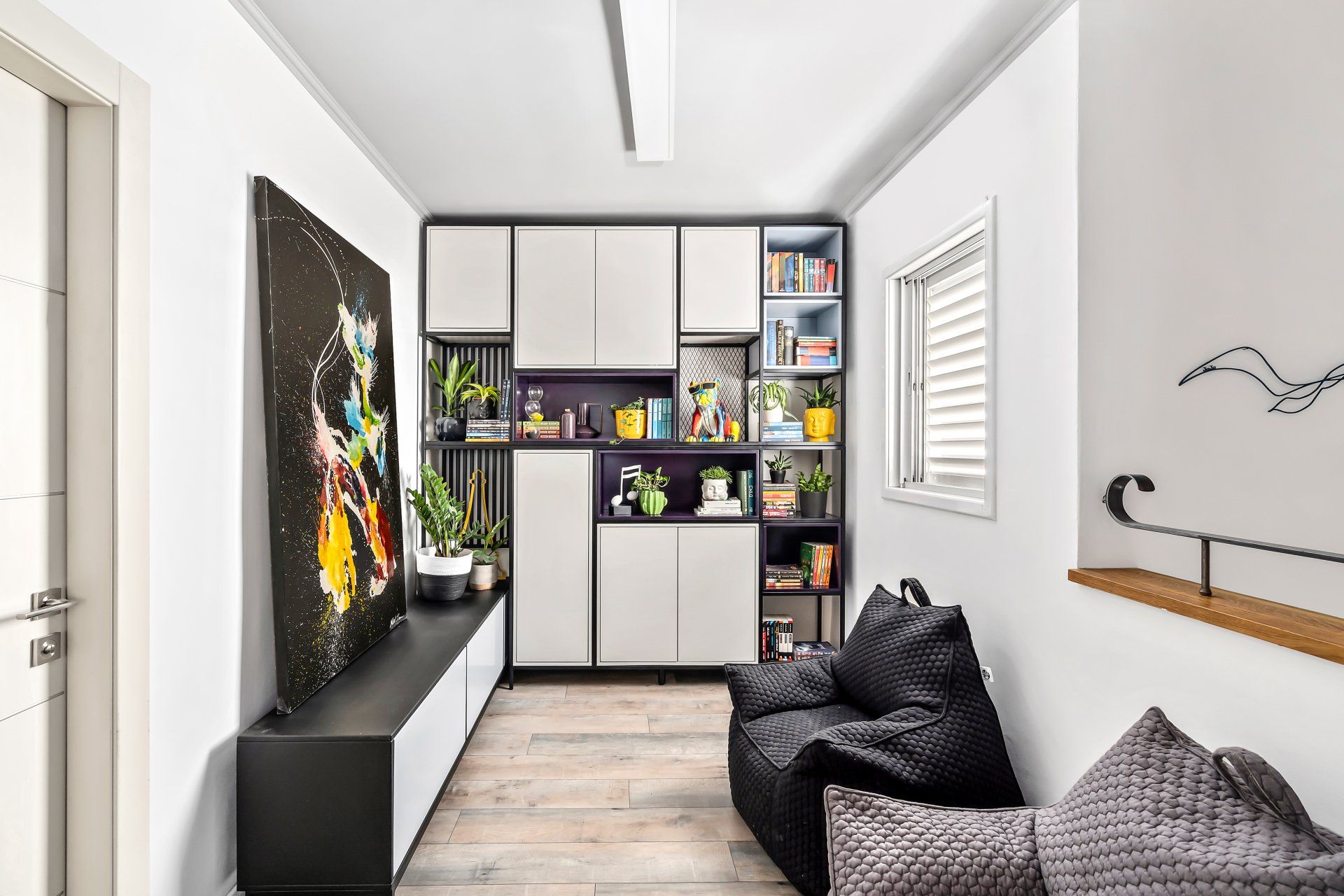 חדר משפחה עם ארון קיר גדול בצבעים של סגול ולבן עם תמונה גדולה צבעונית