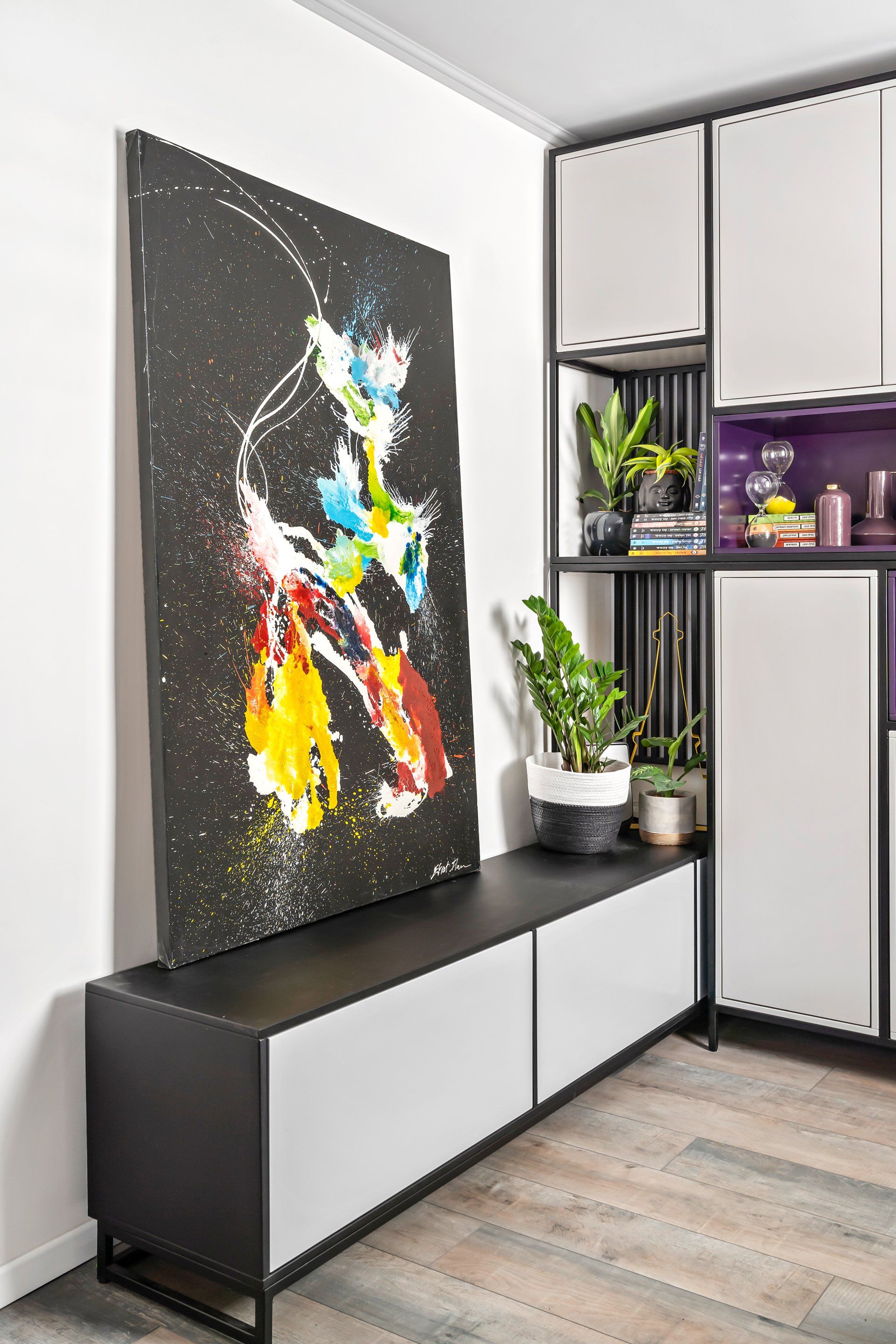 תמונת קיר גדולה צבעונית ואבסטרקטית נשענת מעל שידה