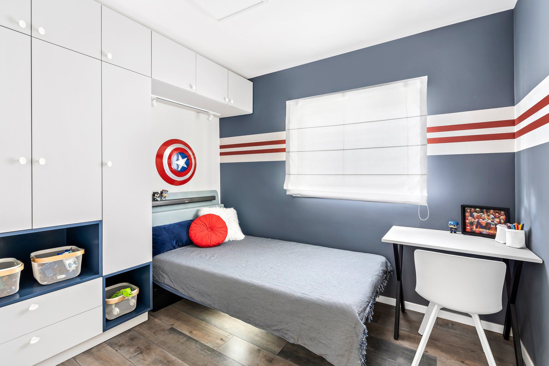 מיטת יחיד אפורה ארון לבן גדול וקיר שצבוע בכחול של קפטן אמריקה