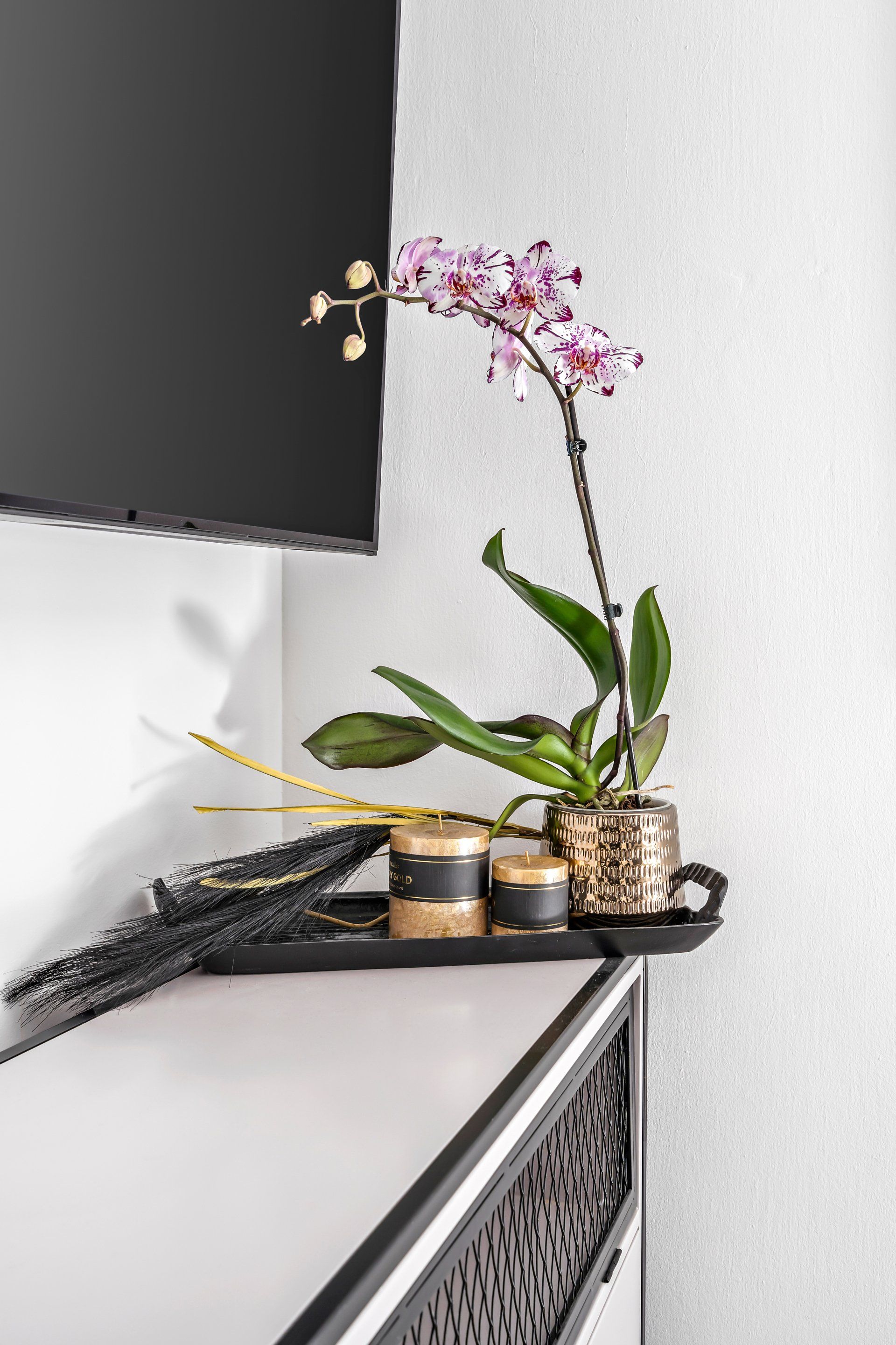 אורכידאה וכלים מוזהבים מעל שידה בחדר שינה