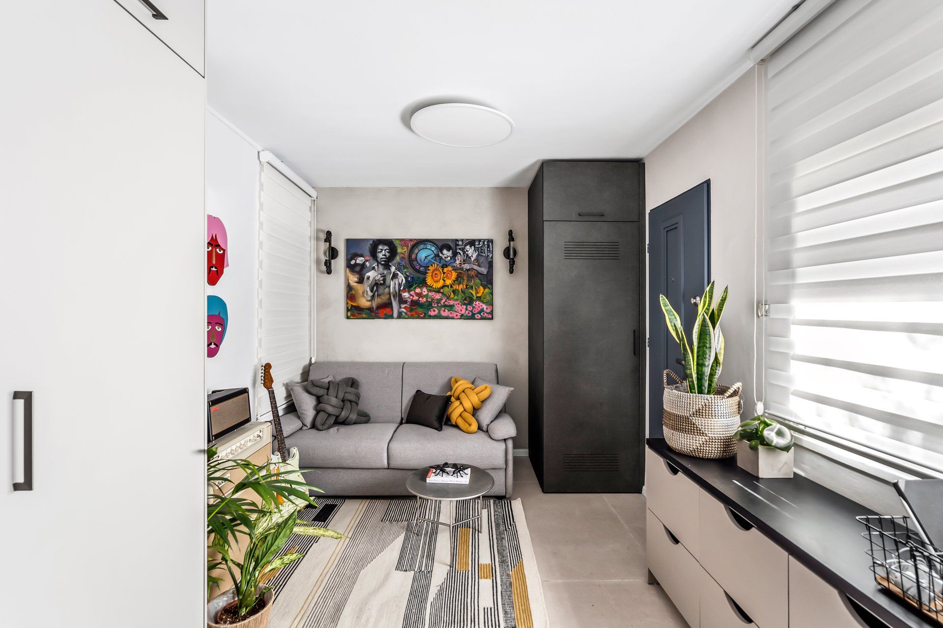 חדר עבודה עם ספה נפתחת ארונית צרה וארוכה בצבע שחור עם נגיעות של צבע צהובהב