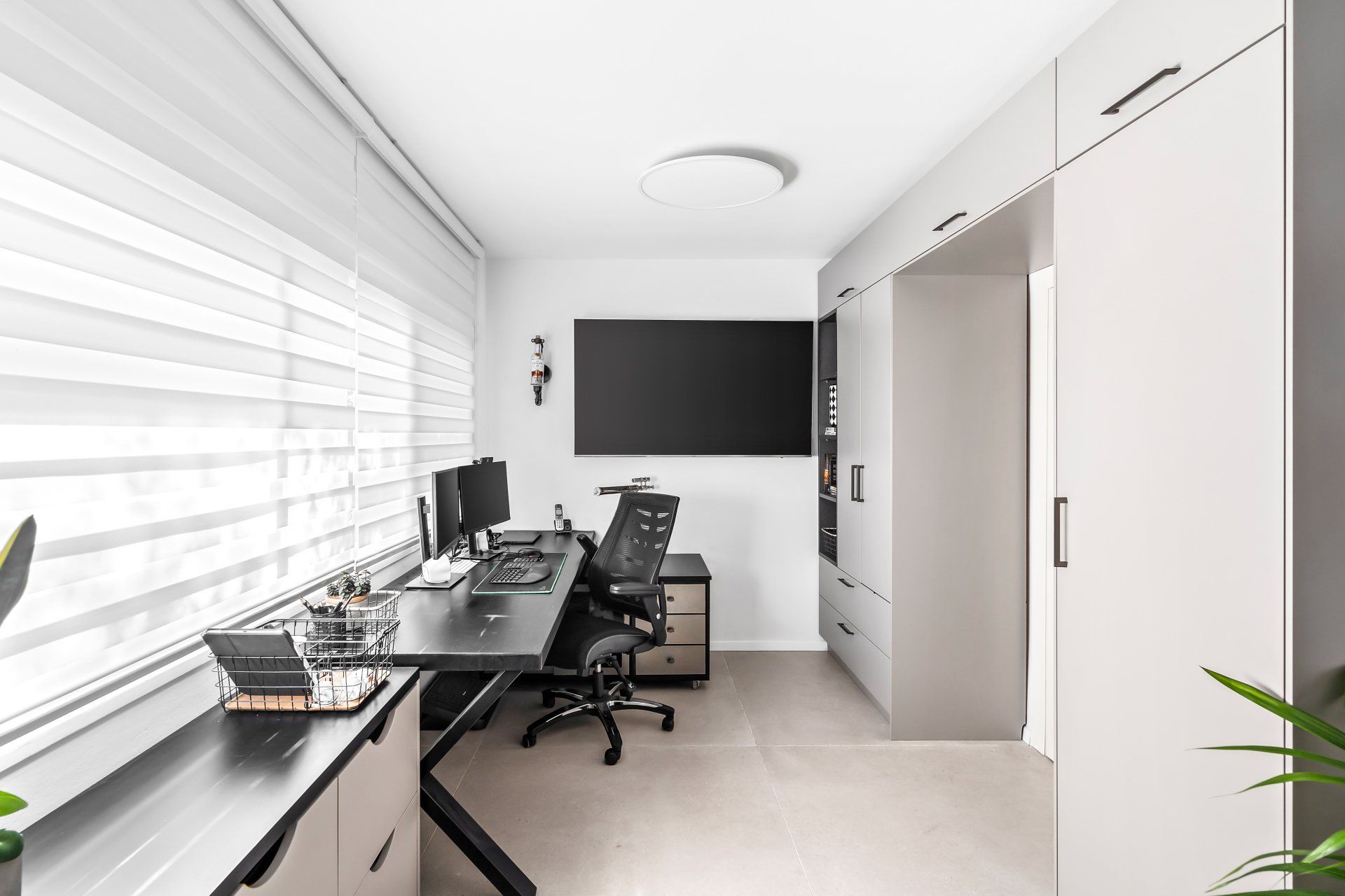 חדר עבודה פרקטי ומודרני עם עמדת מחשב ארון וטלויזיה