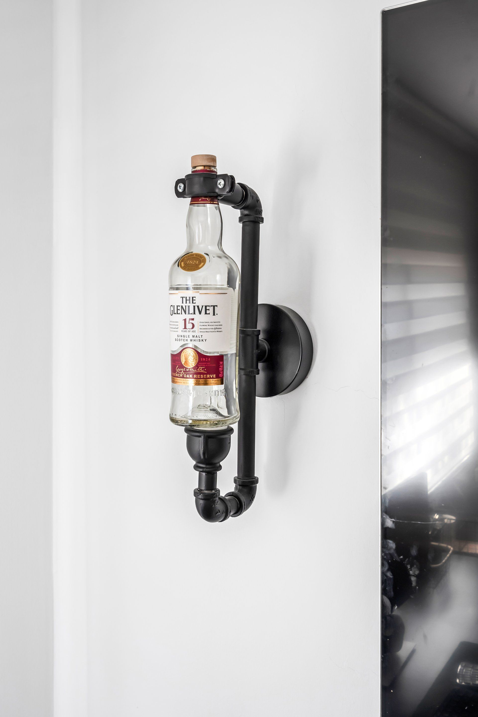 מנורה תלויה על הקיר בצורה של בקבוק ויסקי