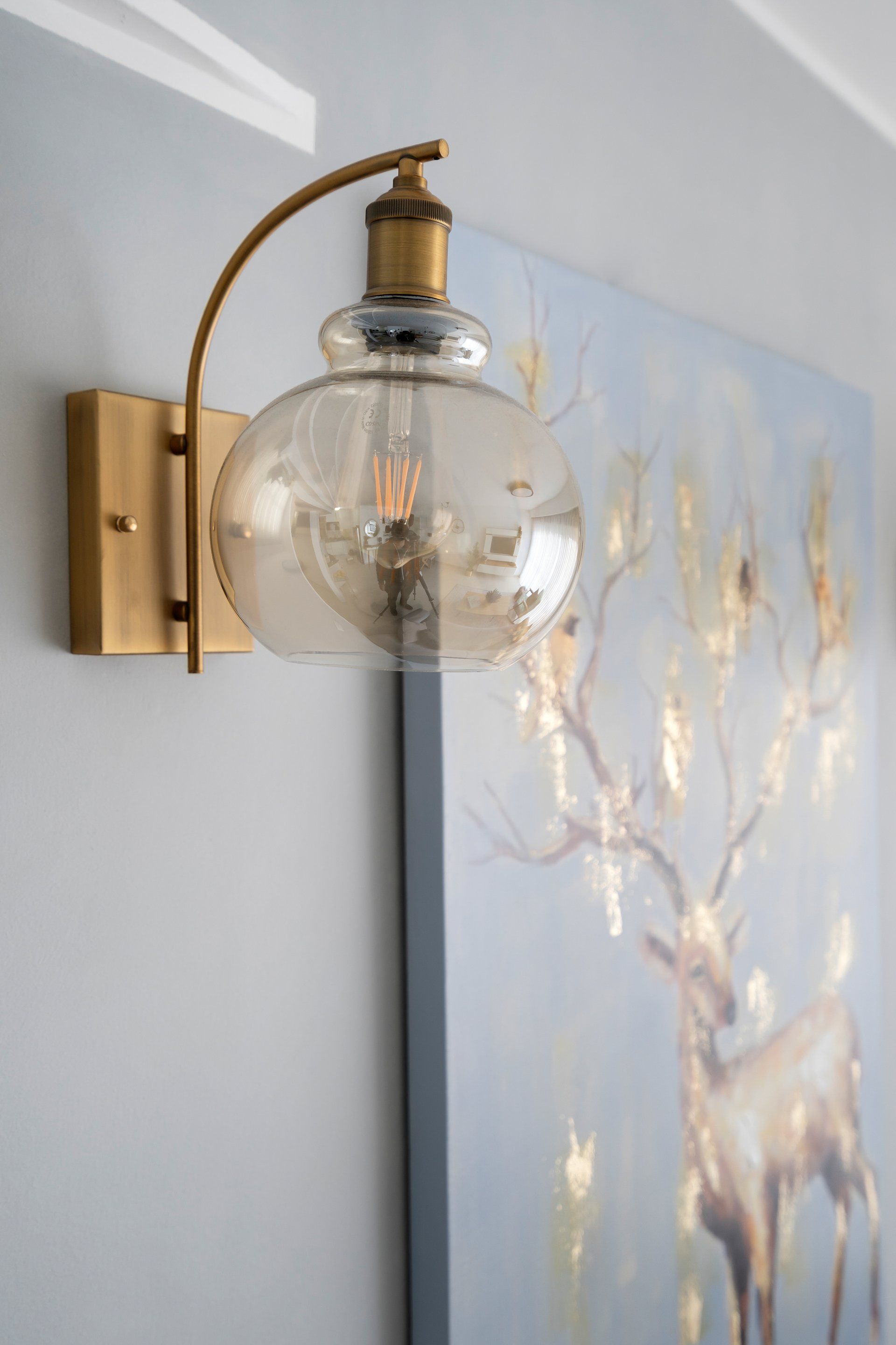 מנורת קריאה תלויה על קיר בגוון מוזהב וזכוכית