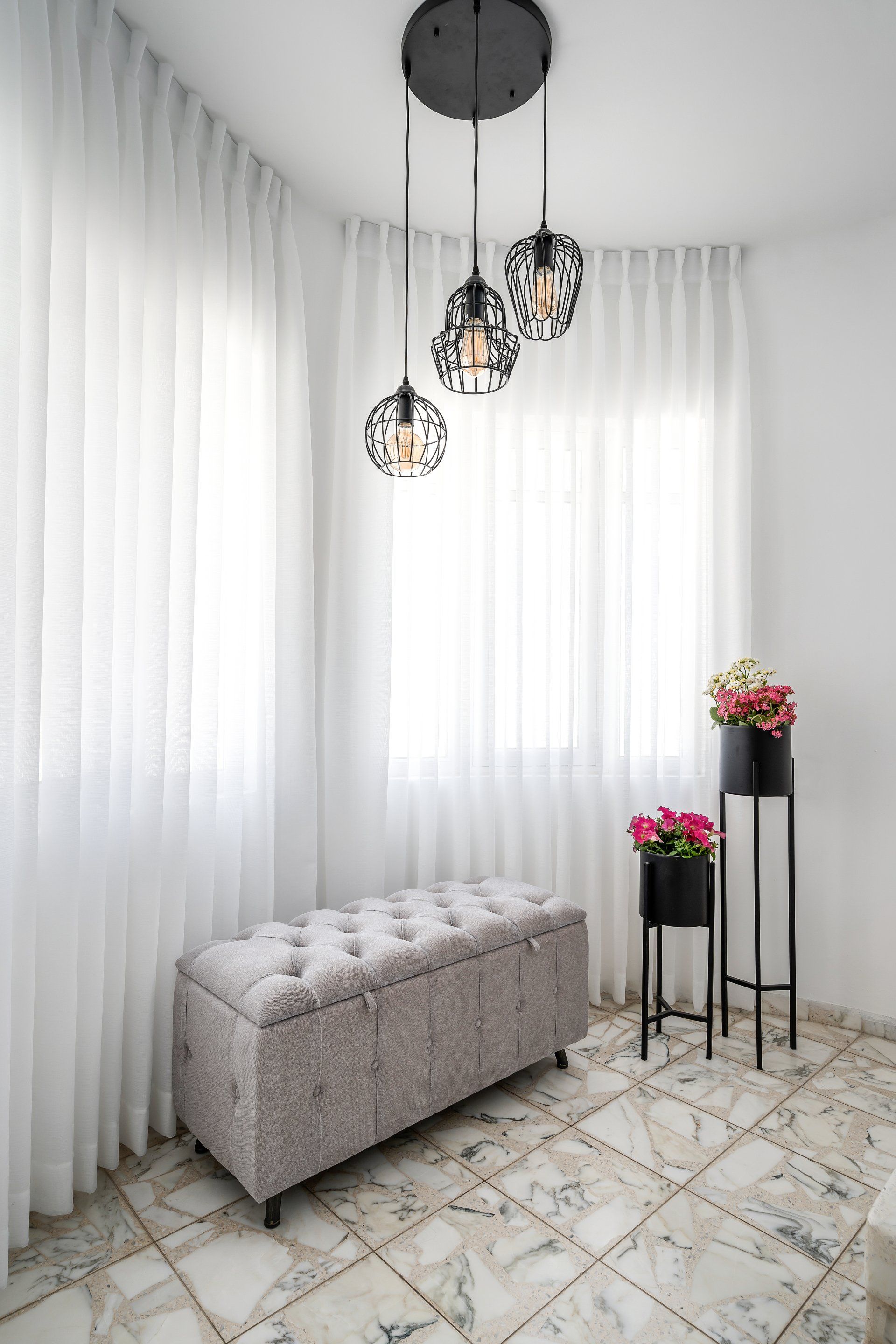 שידה בבית מעוצב עם וילונות לבנים ארוכים וגוף תאורה מהתקרה