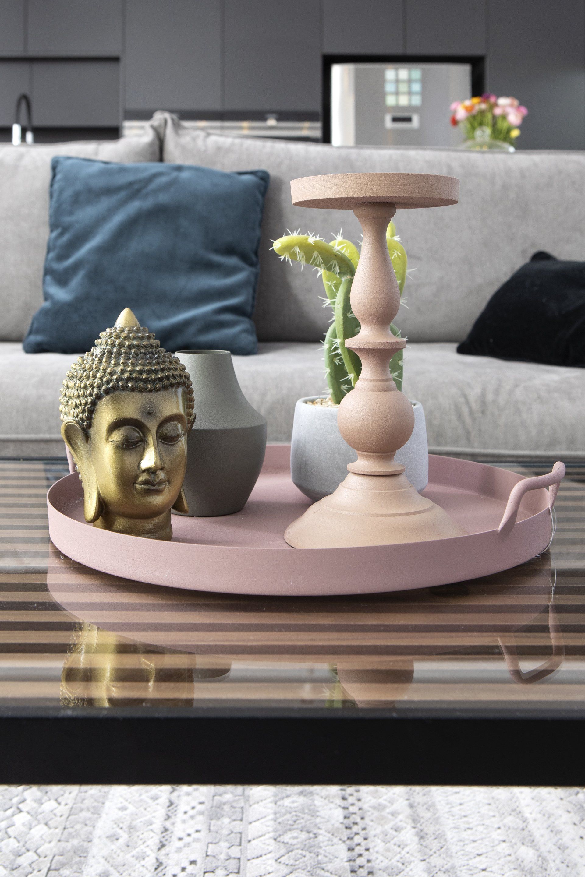 מגש ורוד ועליו פמוט ופסל ראש בודהה מעוצב