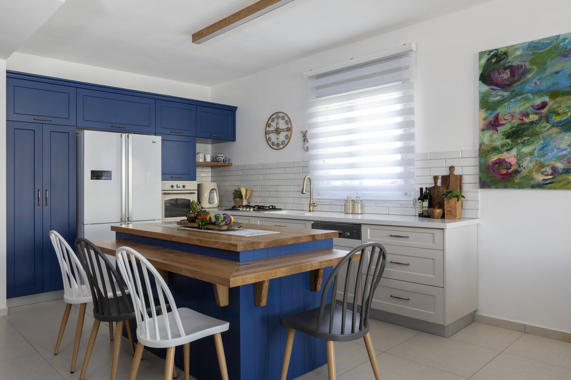 מטבח מעוצב בגוונים של כחול וחום עם אי ישיבה ומקרר לבן