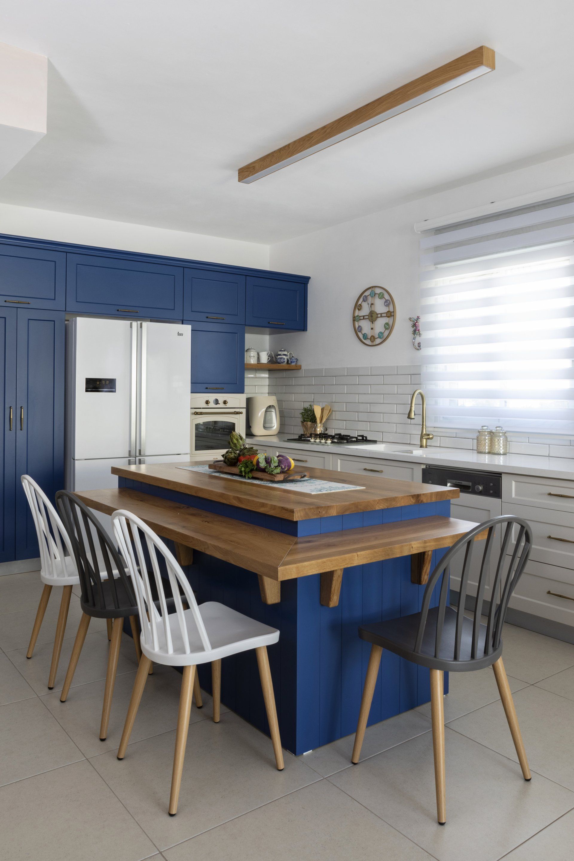 מטבח מעוצב בגוונים של כחול וחום עם אי ישיבה ומקרר לבן