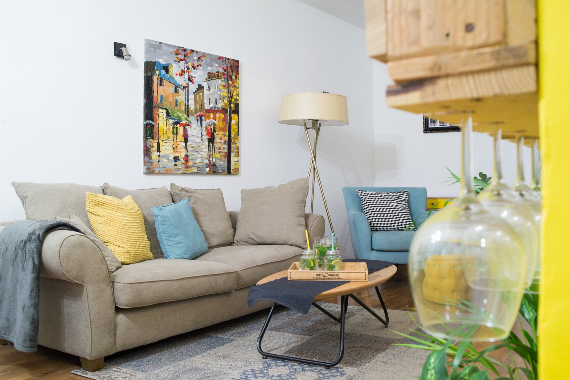 סלון אפרפר וכריות כחולות צהובות מעל הספה יש ציור