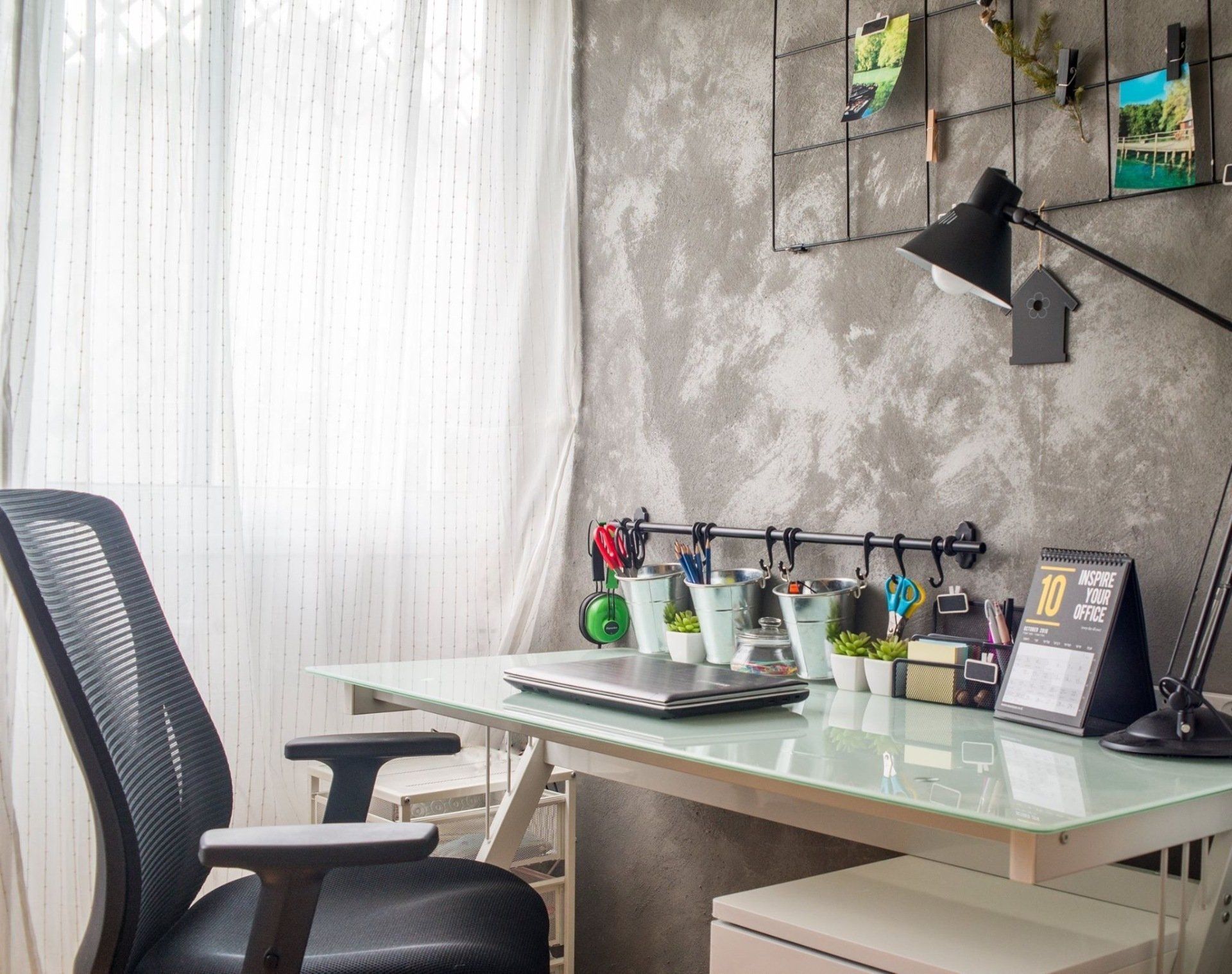 פינת עבודה עם קיר בטון ולפטופ על השולחן