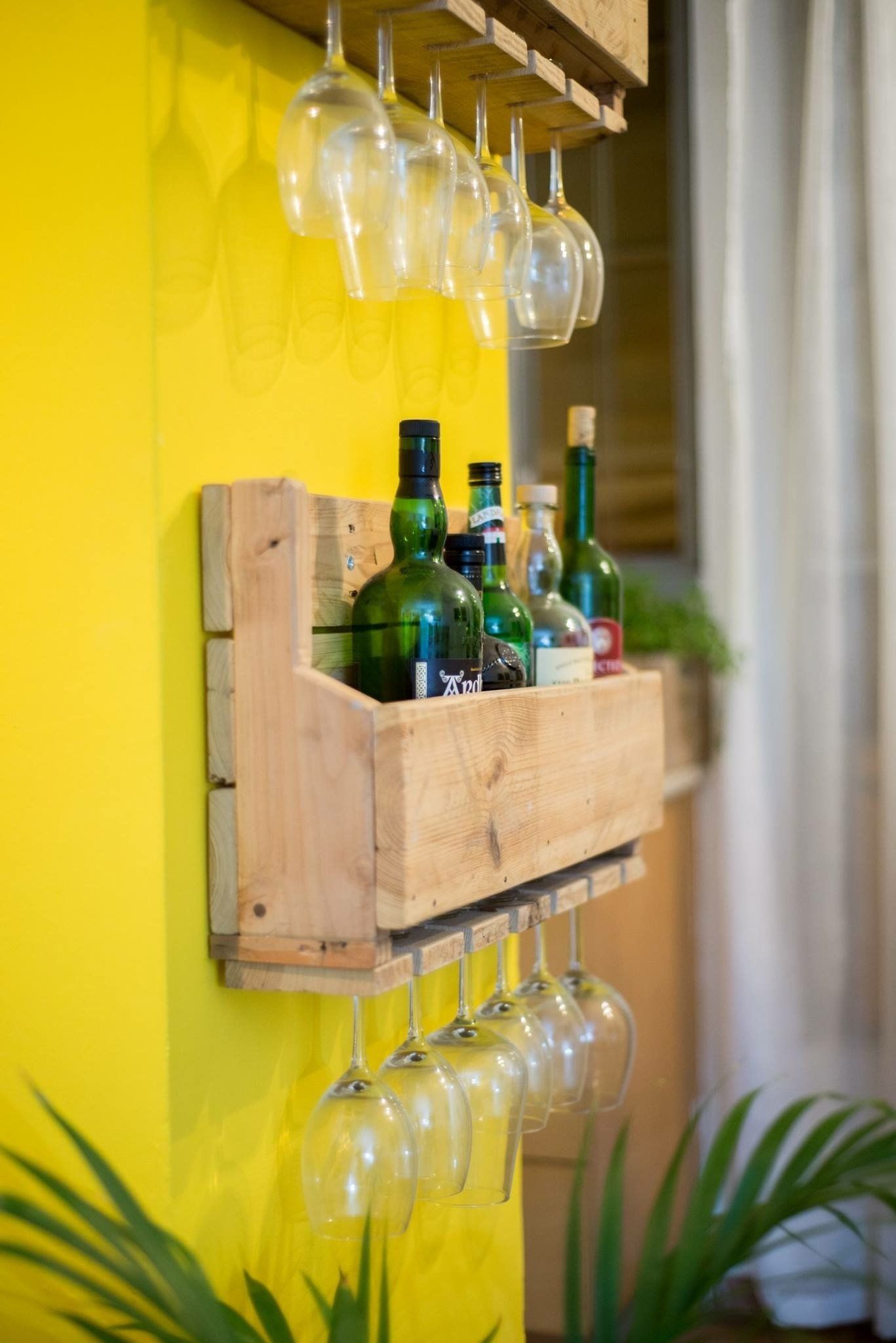 קיר במטבח עם מדף ועליו בקבוקי אלכוהול וכוסות יין