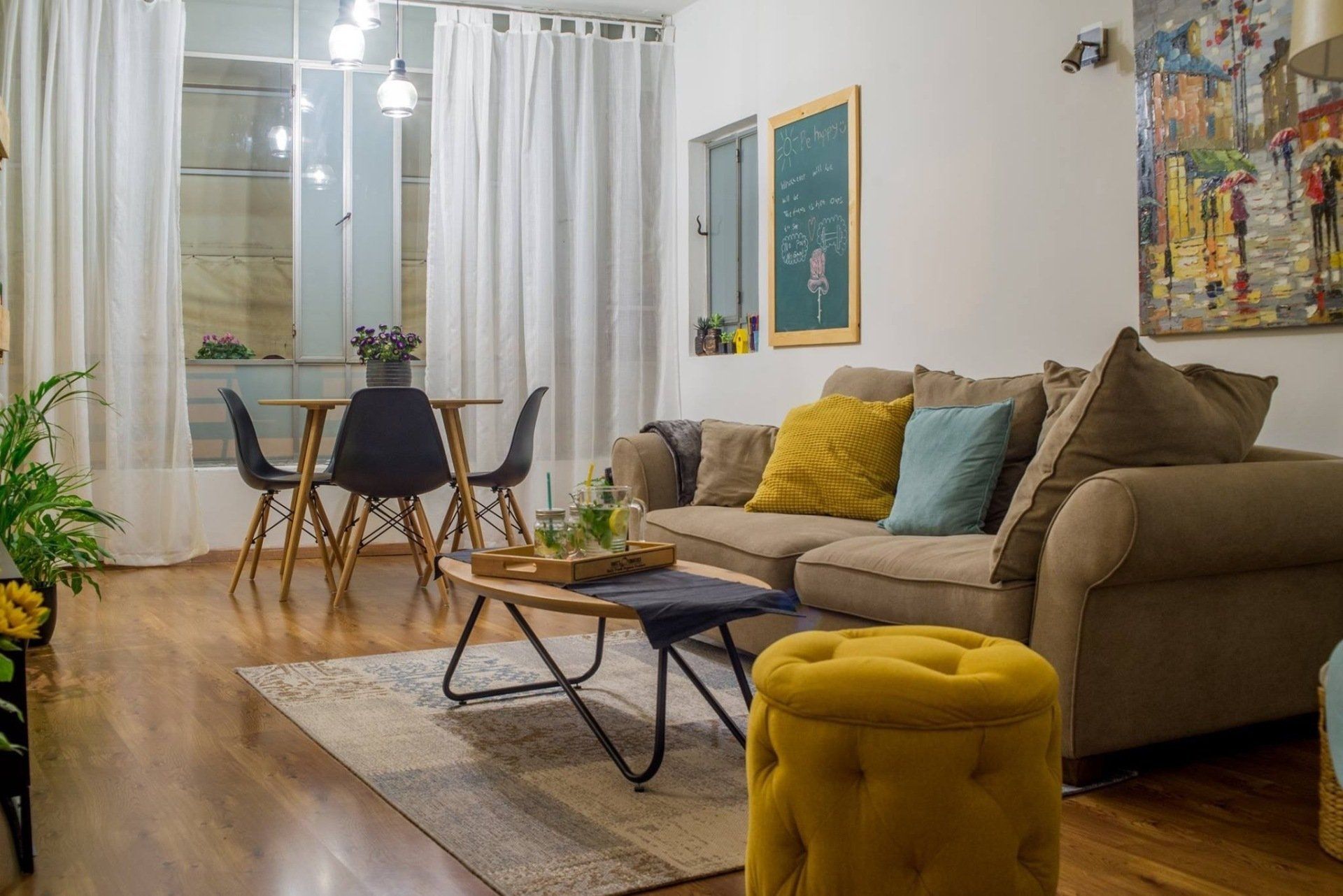 סלון אפור עם כריות צהובות ותכלת עם הדום צהוב ופינת אוכל ברקע