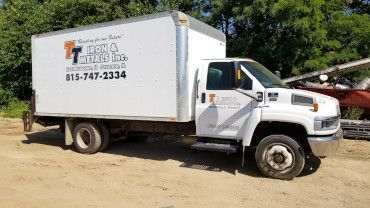 A white box truck parked on a dirt lot, featuring the company name 