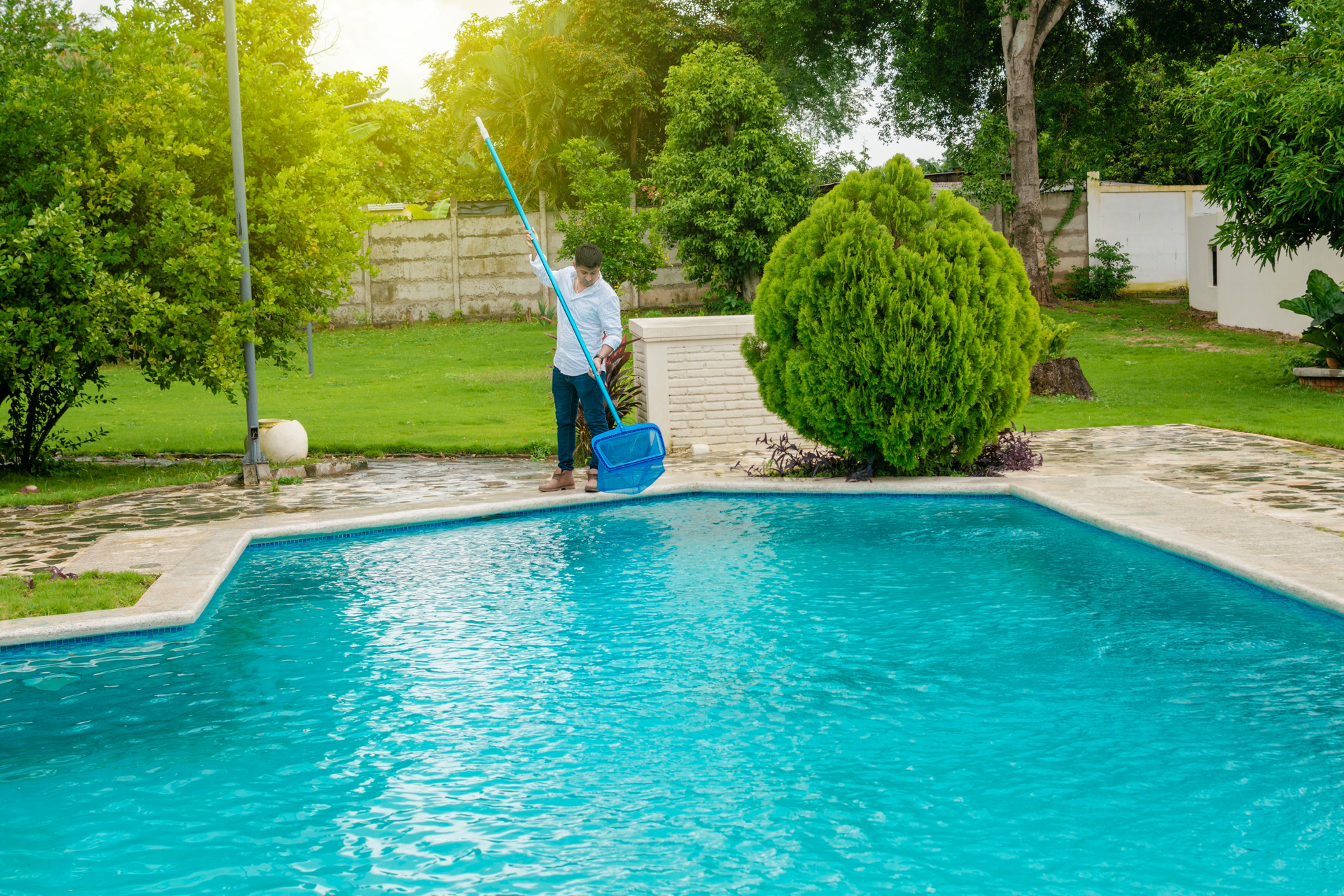 Pool cleaner submerged in a pool, cord and cleaner visible, water blue.