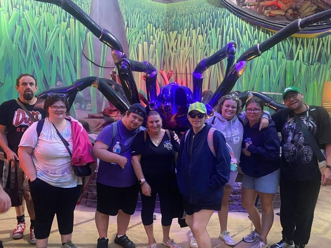 Social and community outings. A group of people are posing for a picture in front of a giant spider.