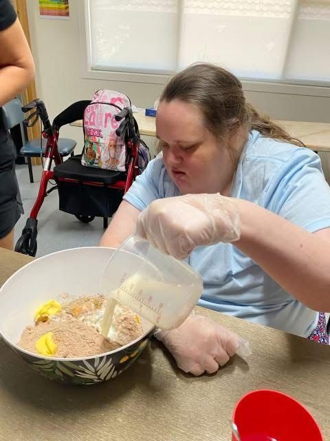 A woman is pouring liquid into a bowl of food