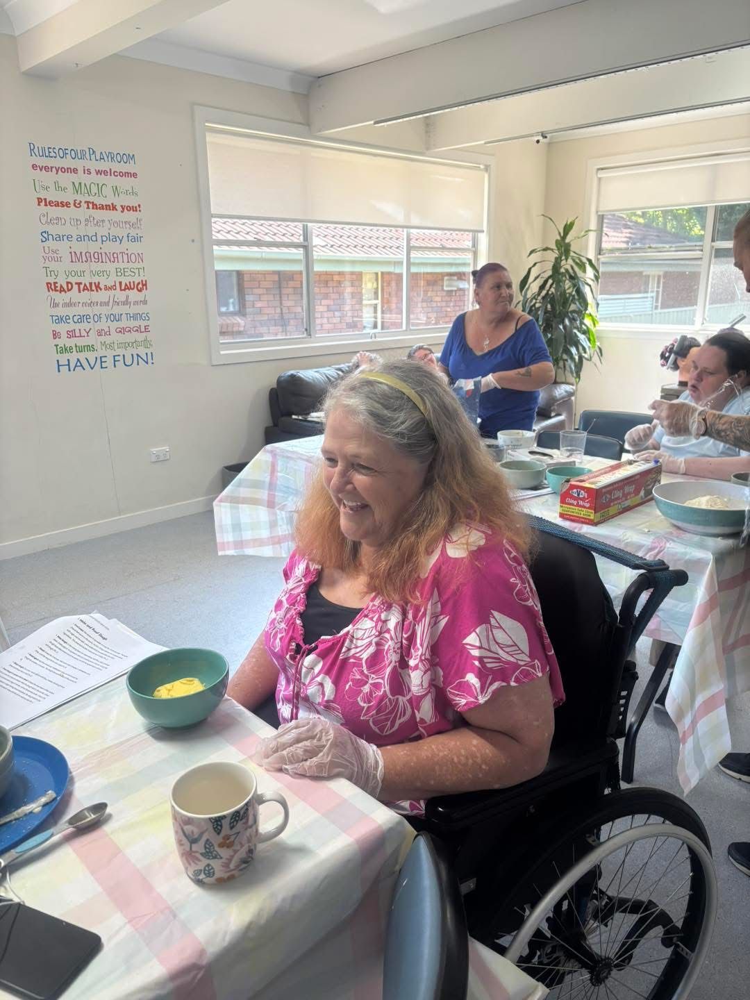 Daily living skills building. Learning to cook. A woman in a wheelchair is sitting at a table with bowls of food.