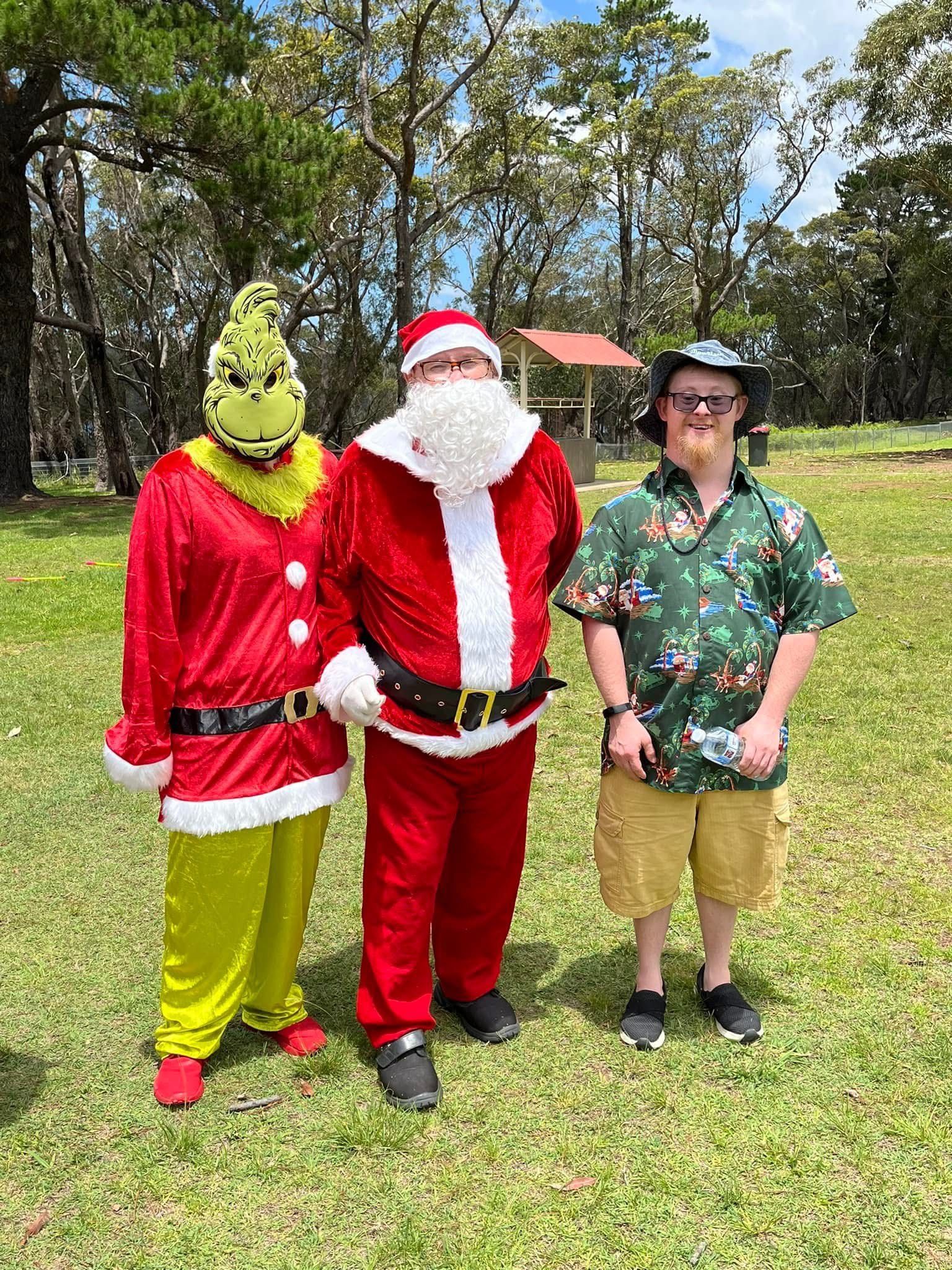 A group of people dressed as santa claus and the grinch are standing next to each other in a field.
