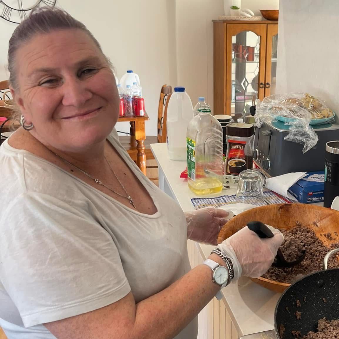 Respite In-home and Short Stay Accommodation. A woman is smiling while holding a bowl of food.