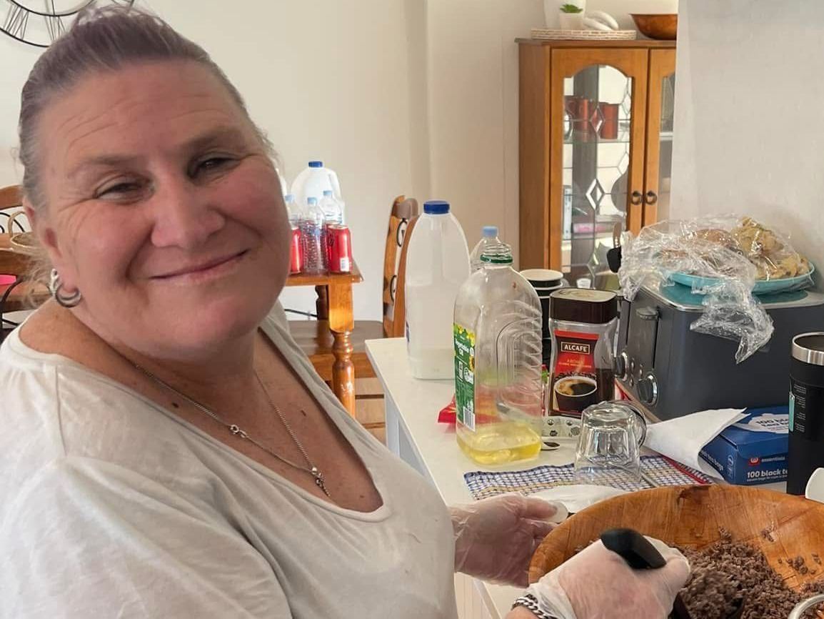 Daily Activities and skill building woman in a white shirt is smiling in a kitchen cooking.