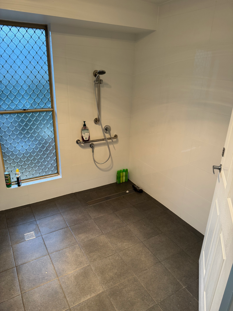 A modified bathroom with a shower and a window for disability access.