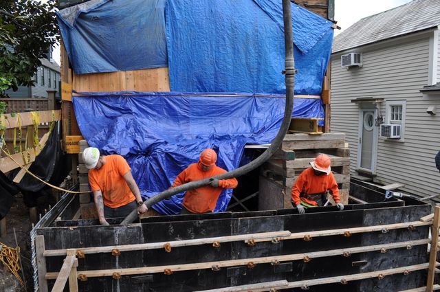 a group of construction workers are working on a building under a blue tarp