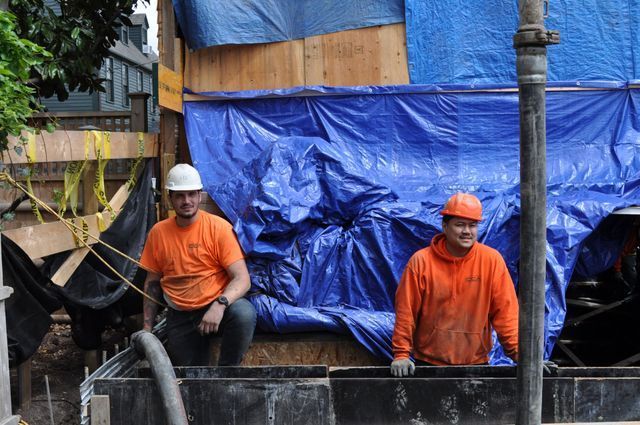 two construction workers are standing in front of a blue tarp