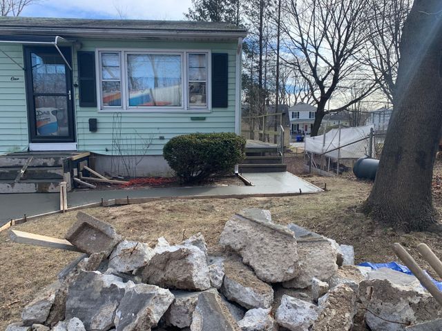 a pile of rocks sits in front of a house to show beginning of concrete sidewalk project